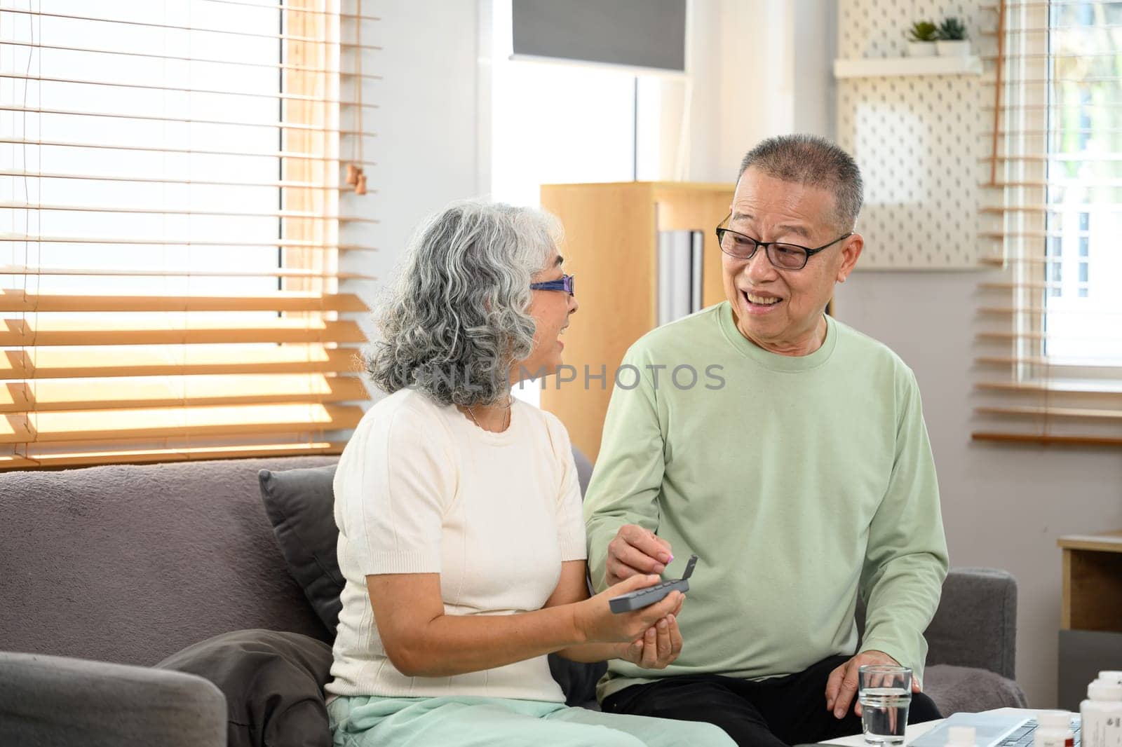 Elderly couple taking daily supplements or medications from a pill organizer box.
