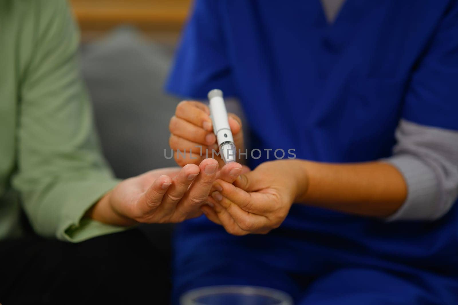 Unrecognizable female nurse checking blood sugar of diabetic elderly patient.