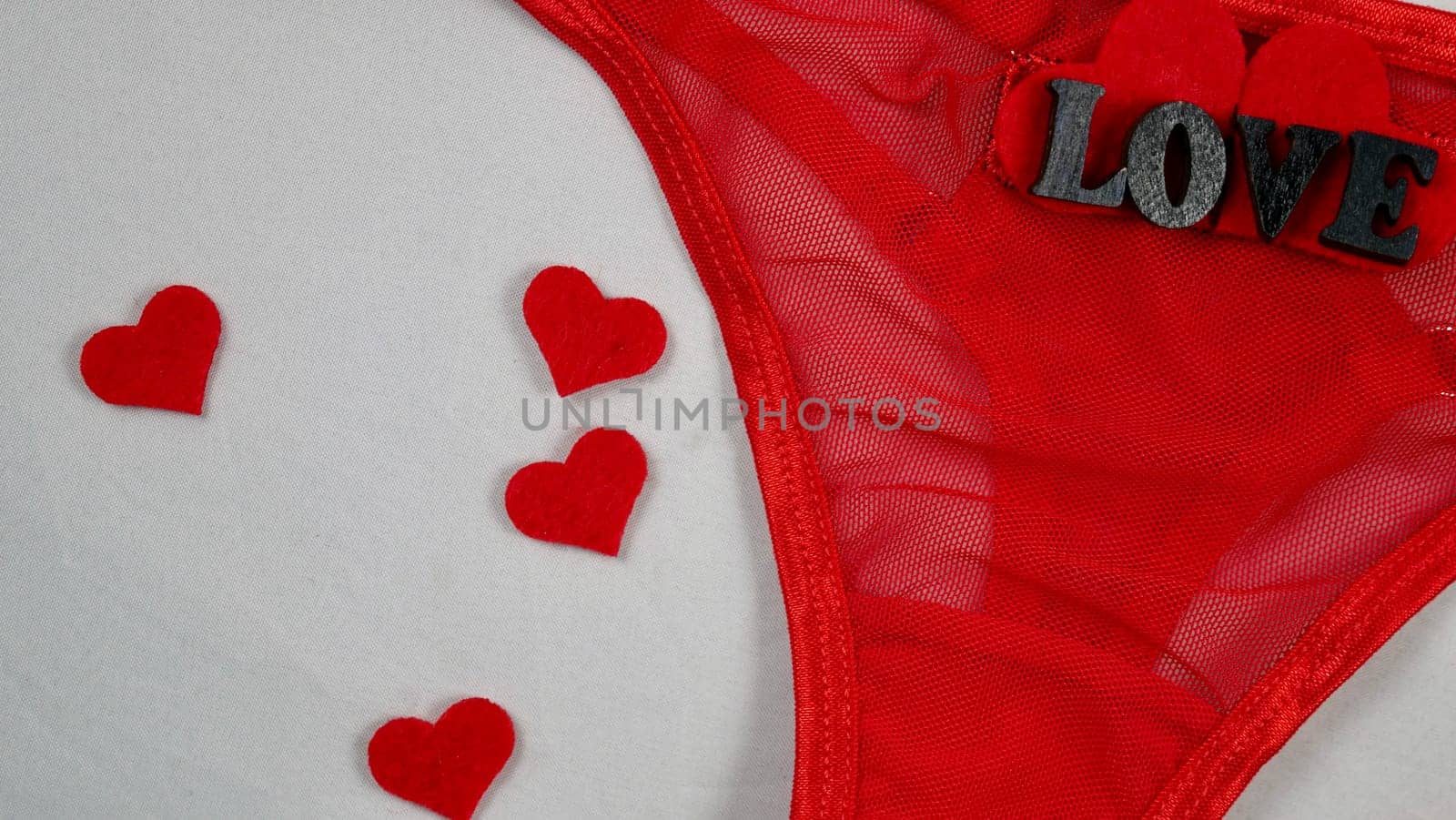 Valentine's Day Sexy Underwear Red Mesh Micro Panties Thong Hold Up String. Close-up in focus on white isolated background. with hearts
