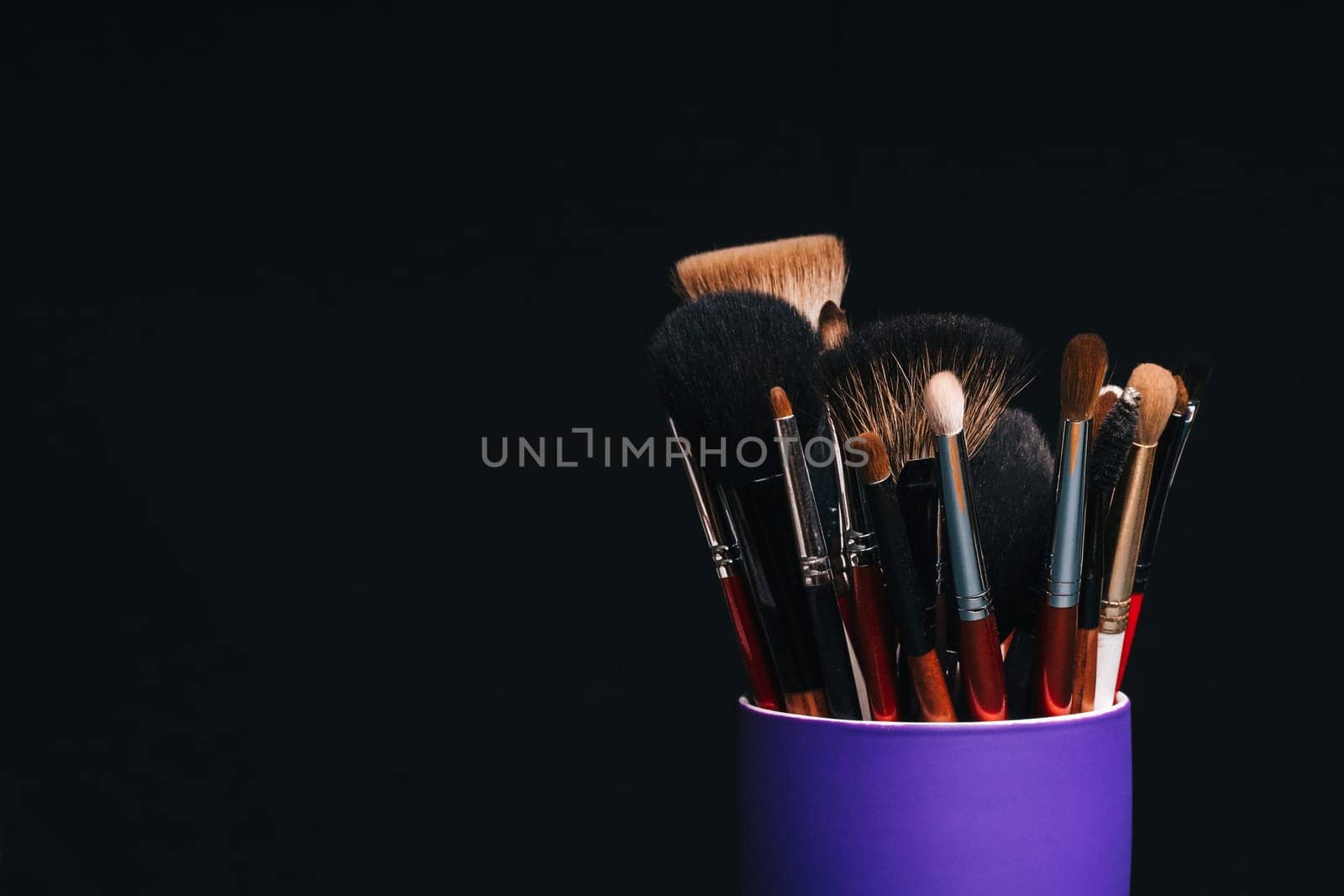 set of professional makeup brushes close up with copy space on dark background