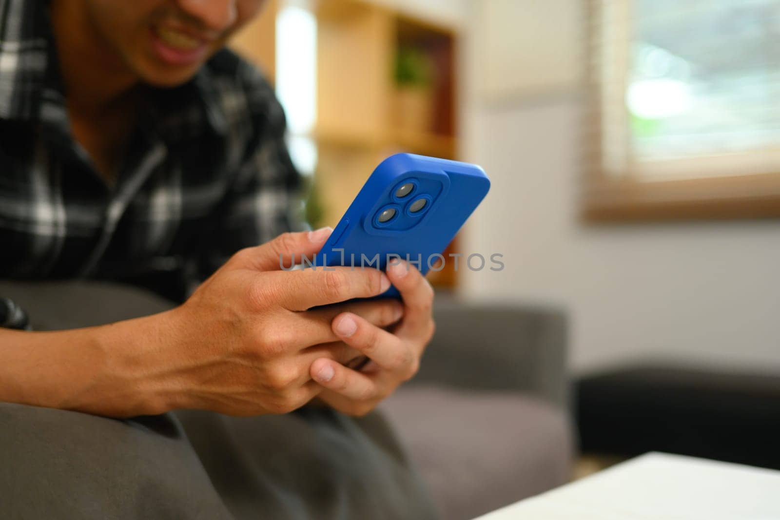 Close up shot of smiling man scrolling news in social media on mobile phone.