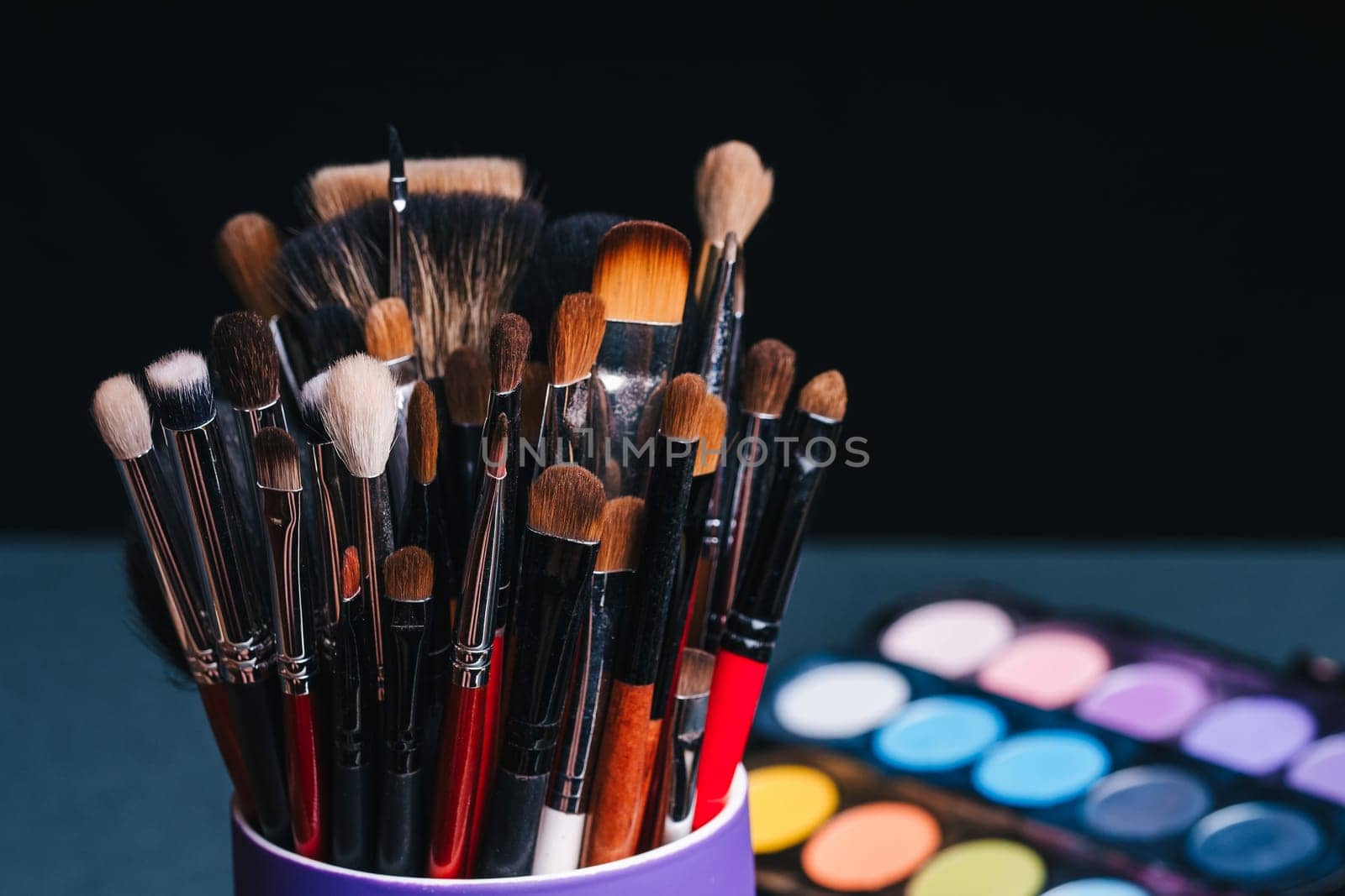 set of makeup brushes on the background of a professional palette with eye shadows close-up. The concept of women's cosmetics for beauty