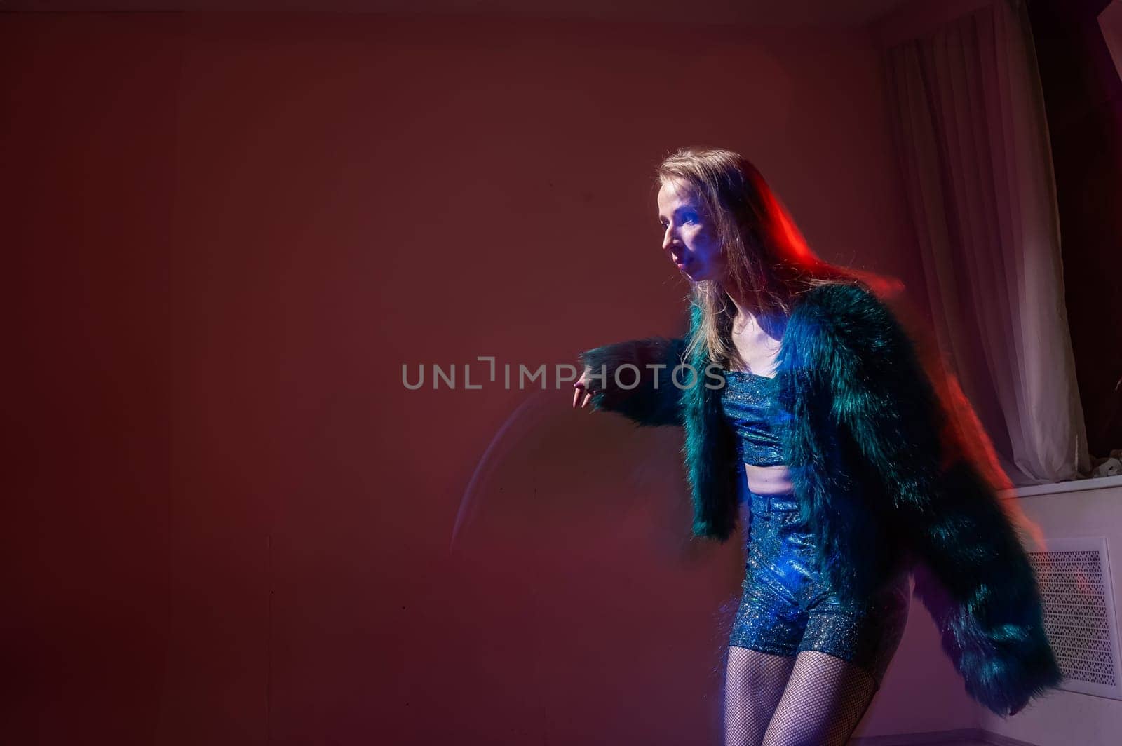 A young woman dances contemporary dances in blue and red light. Long exposure photo. by mrwed54