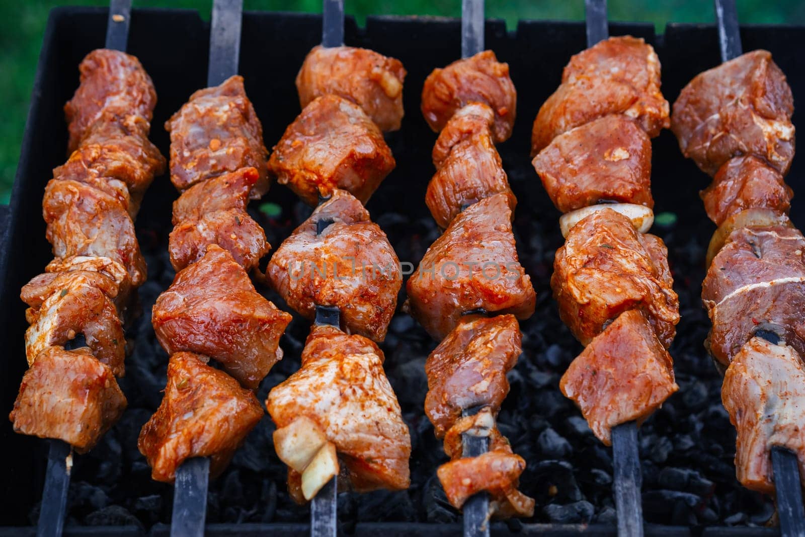 barbecue of pork is prepared on skewers on the grill for a summer picnic