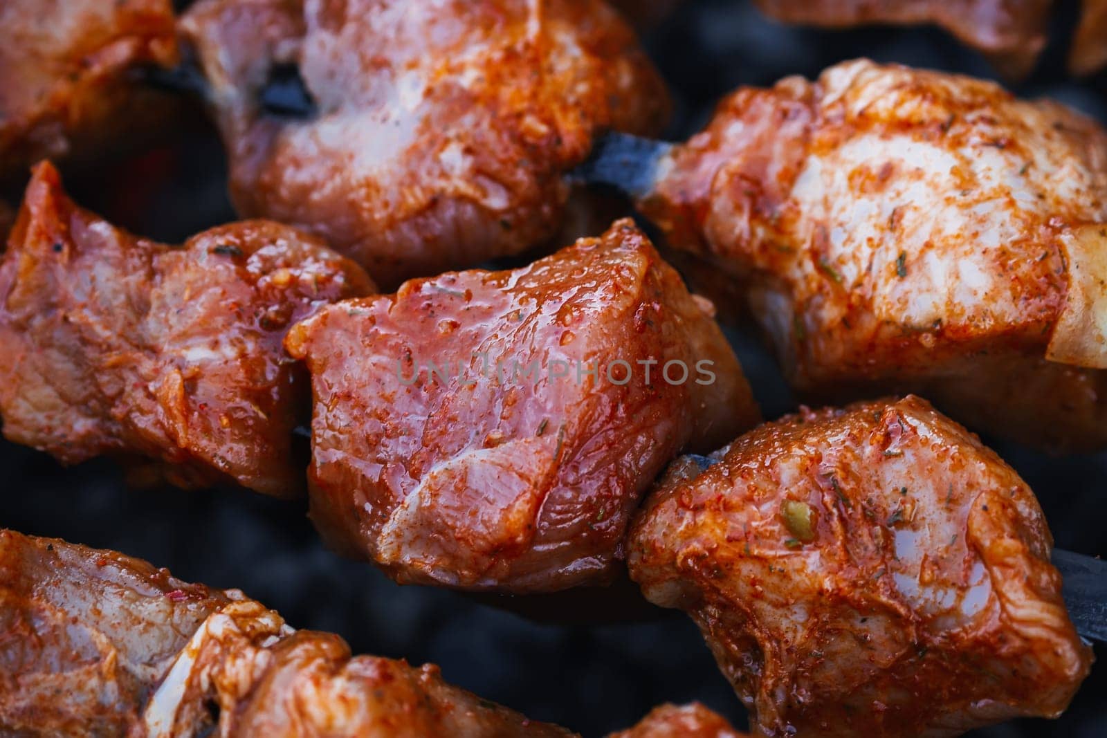 pork meat is cooked on skewers on barbecue grill close-up