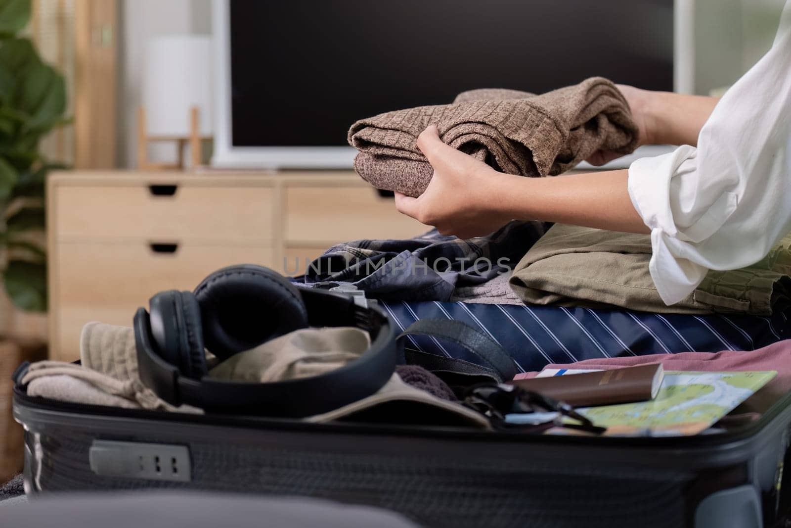 Suitcase with clothes packed for journey at home. asian woman packing bag for holiday and preparing things for vacation getting ready for travel by nateemee
