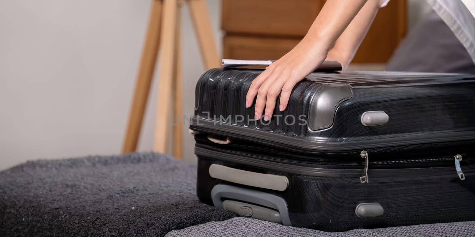 Young woman asian traveler sitting on the sofa packing her suitcase preparing for travel on summer vacation.