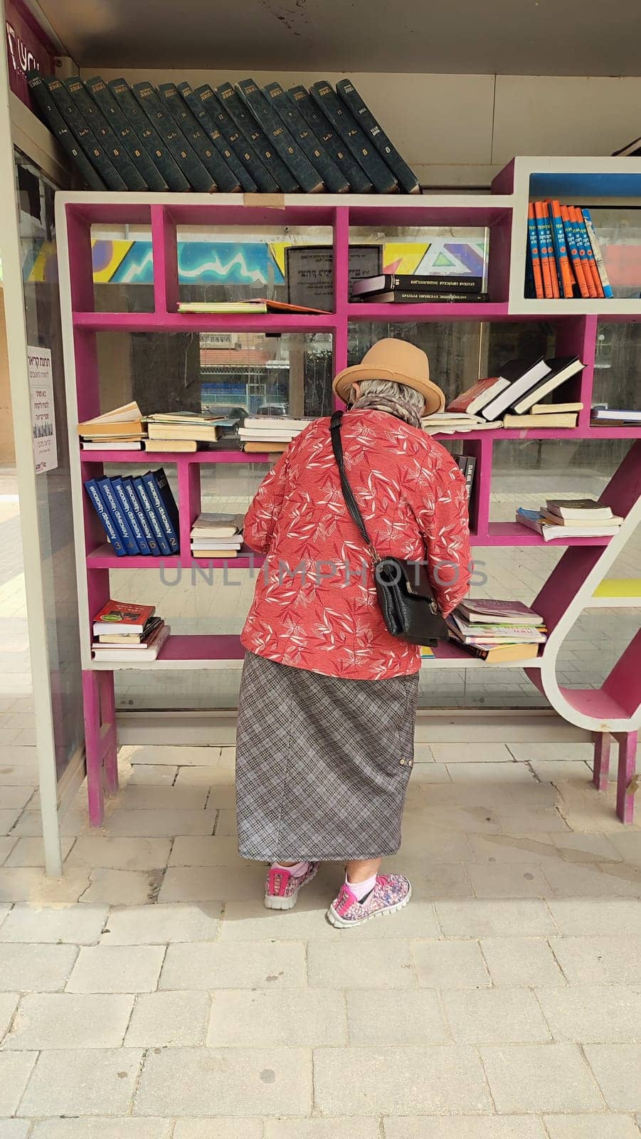 18 April 2024 Beersheva Israel, woman choosing books on a street bookshelf by Ply