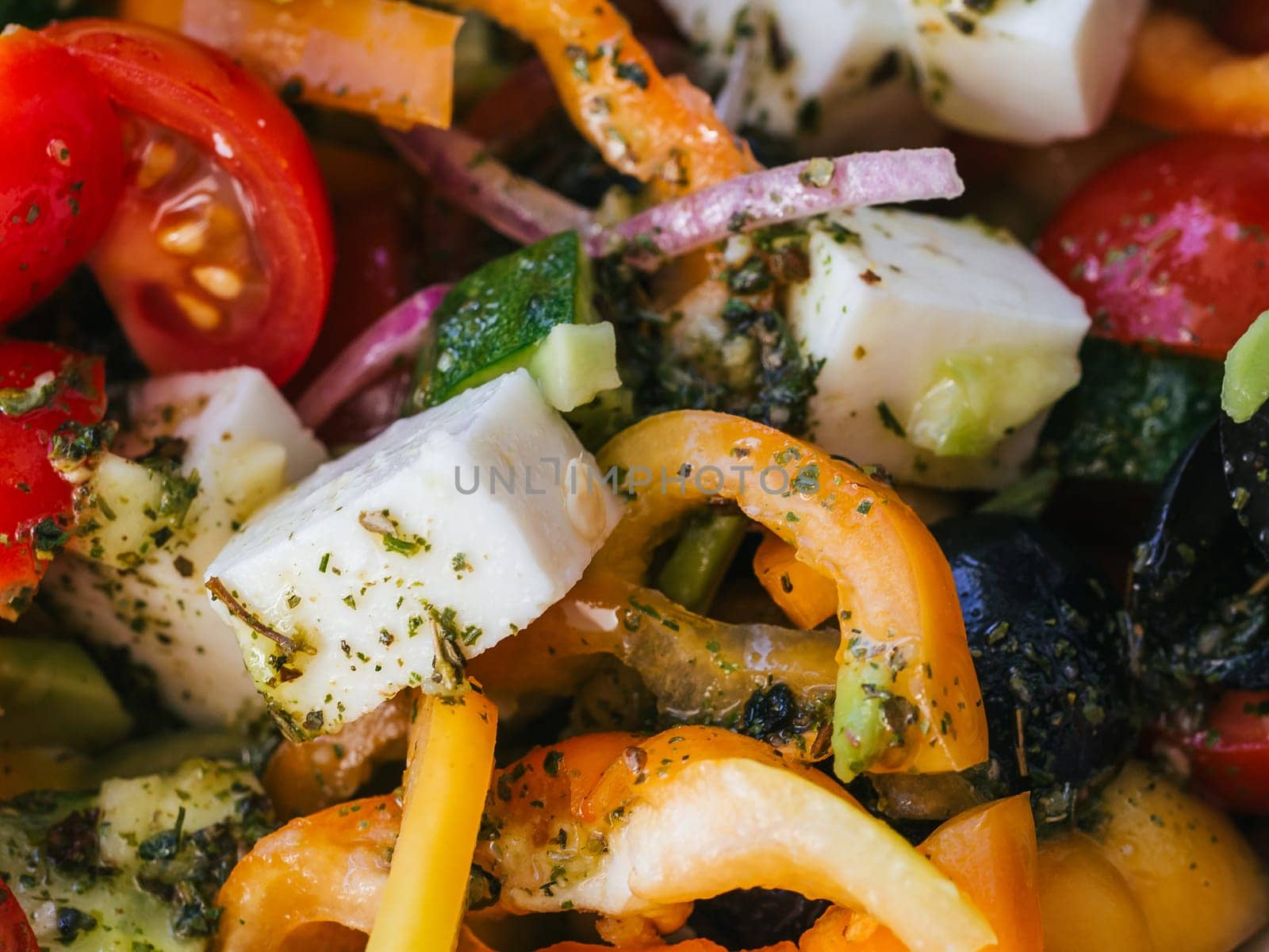 Greek salad with tomatoes, cucumbers, bell peppers, feta cheese and other ingredients close-up