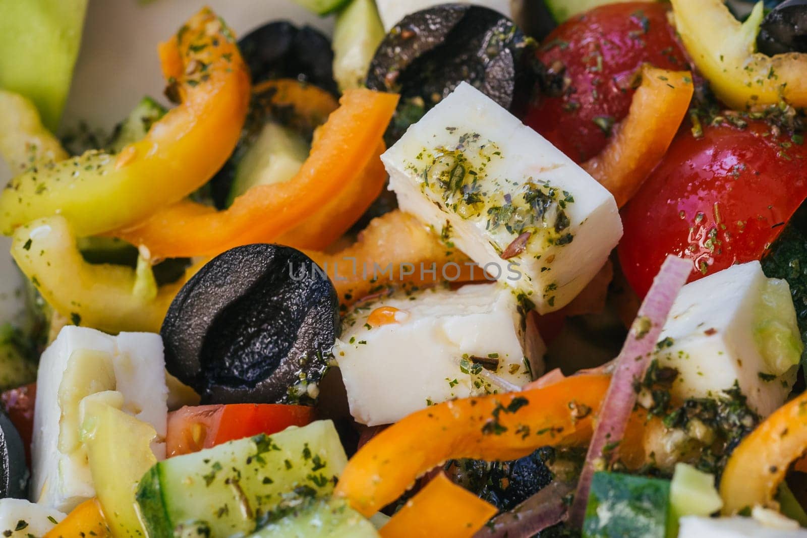 Greek salad with tomatoes, cucumbers, bell peppers, feta cheese and other ingredients close-up