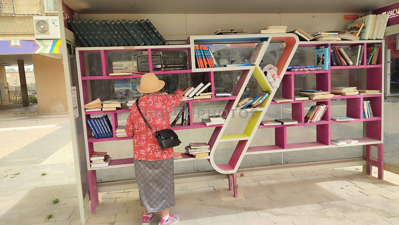 18 April 2024 Beersheva Israel, woman choosing books on a street bookshelf. High quality photo