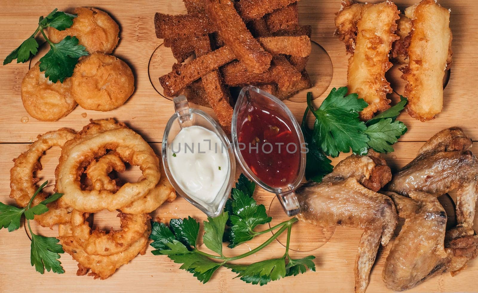 breaded appetizers, fried chicken wings and breadcrumbs with sauce on a wooden Board