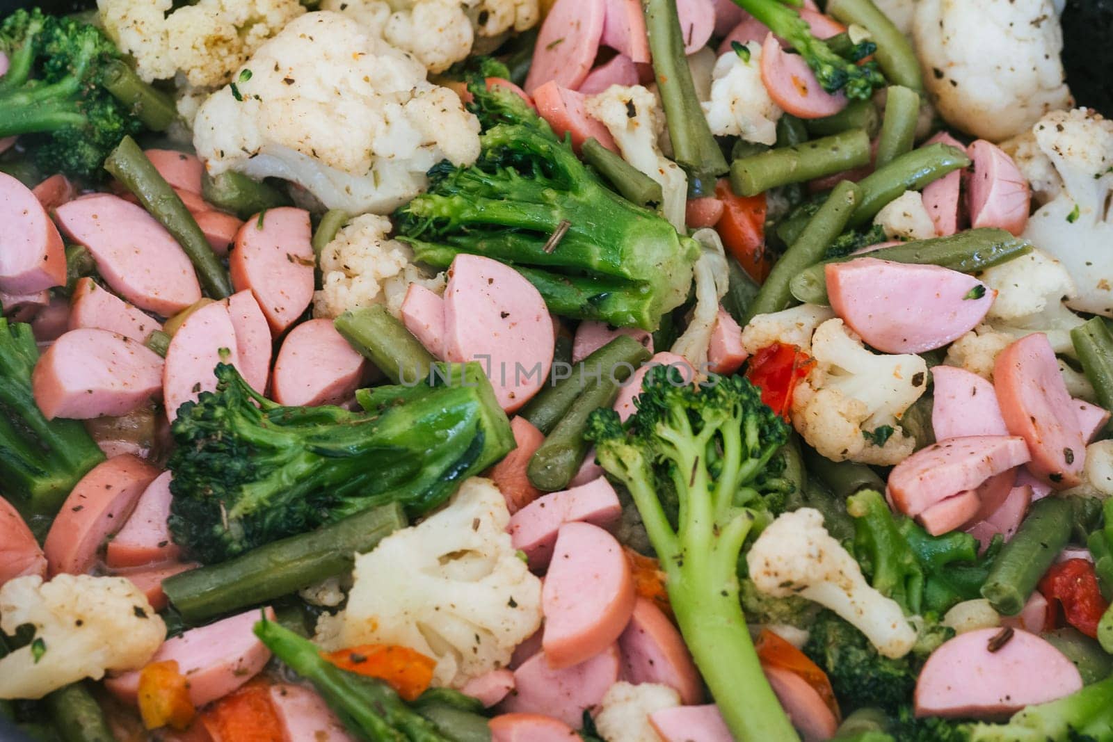 sausages with vegetables fried in a frying pan close-up