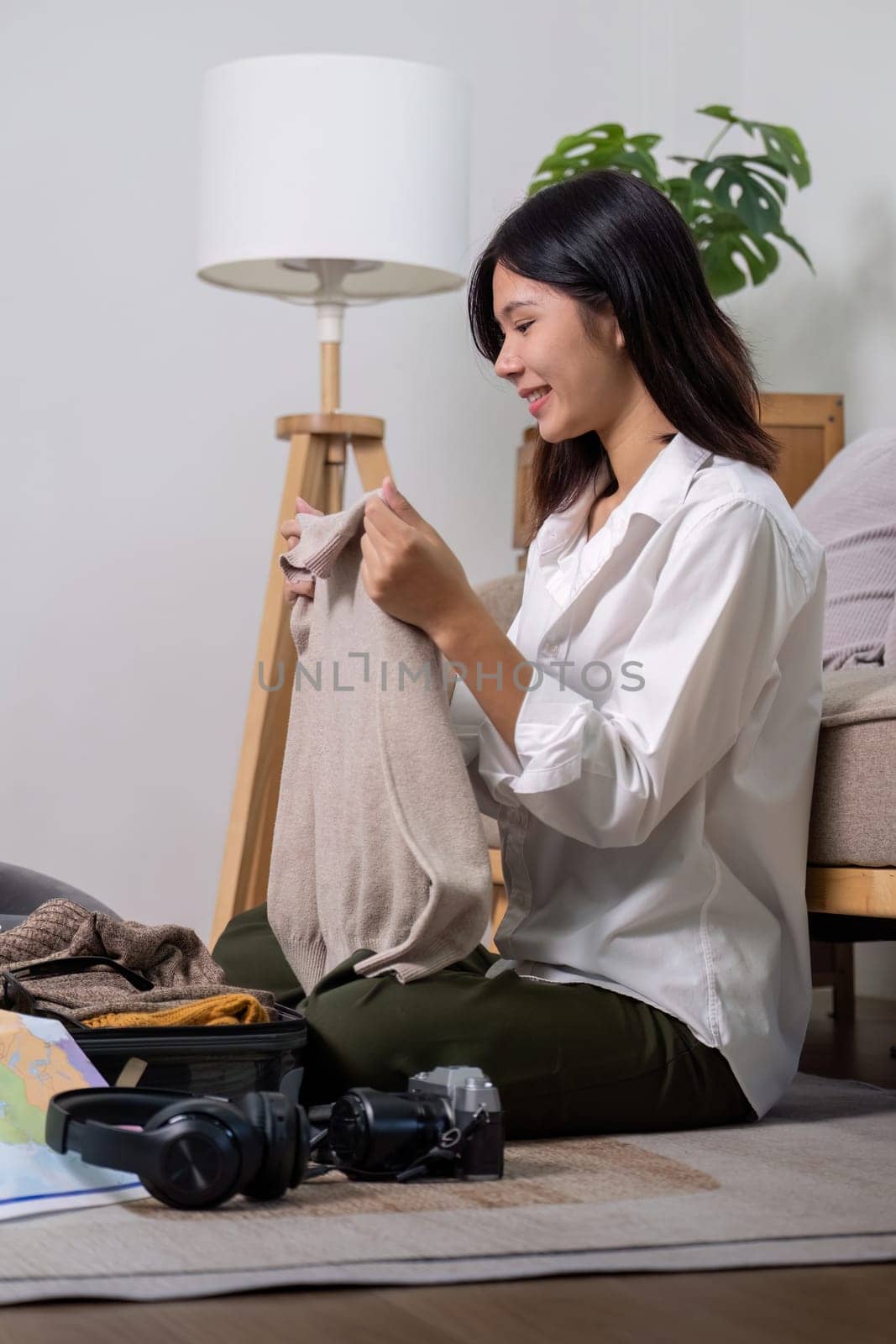 Young woman asian traveler sitting on the floor packing her suitcase preparing for travel on summer vacation.