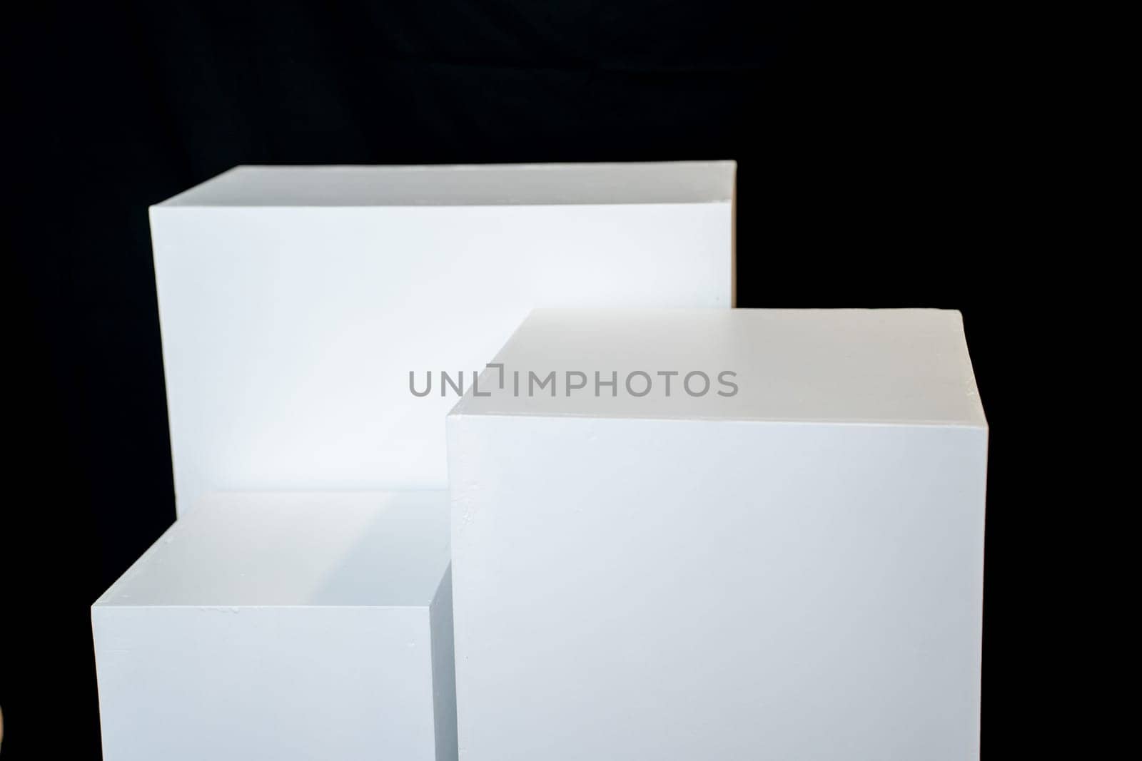Three white rectangular boxes against a green wall with shadows. Product photography background. Pedestal for cosmetic product and packaging mockups display presentation. High quality photo