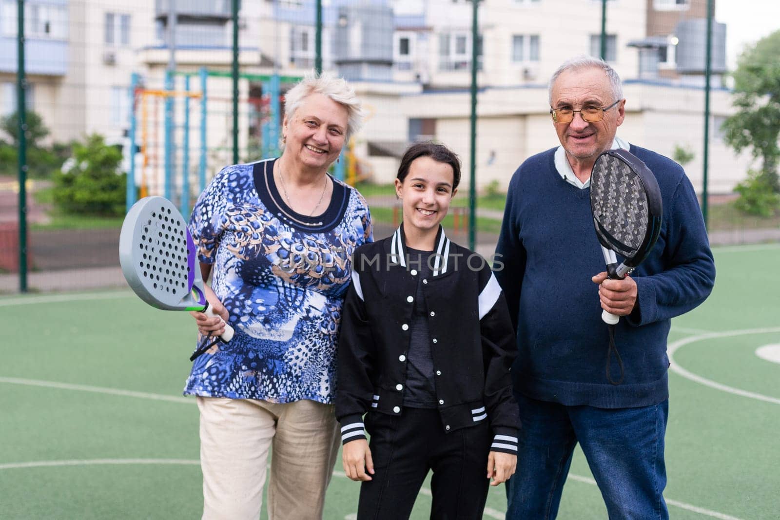 an old couple and a granddaughter play padel tennis by Andelov13
