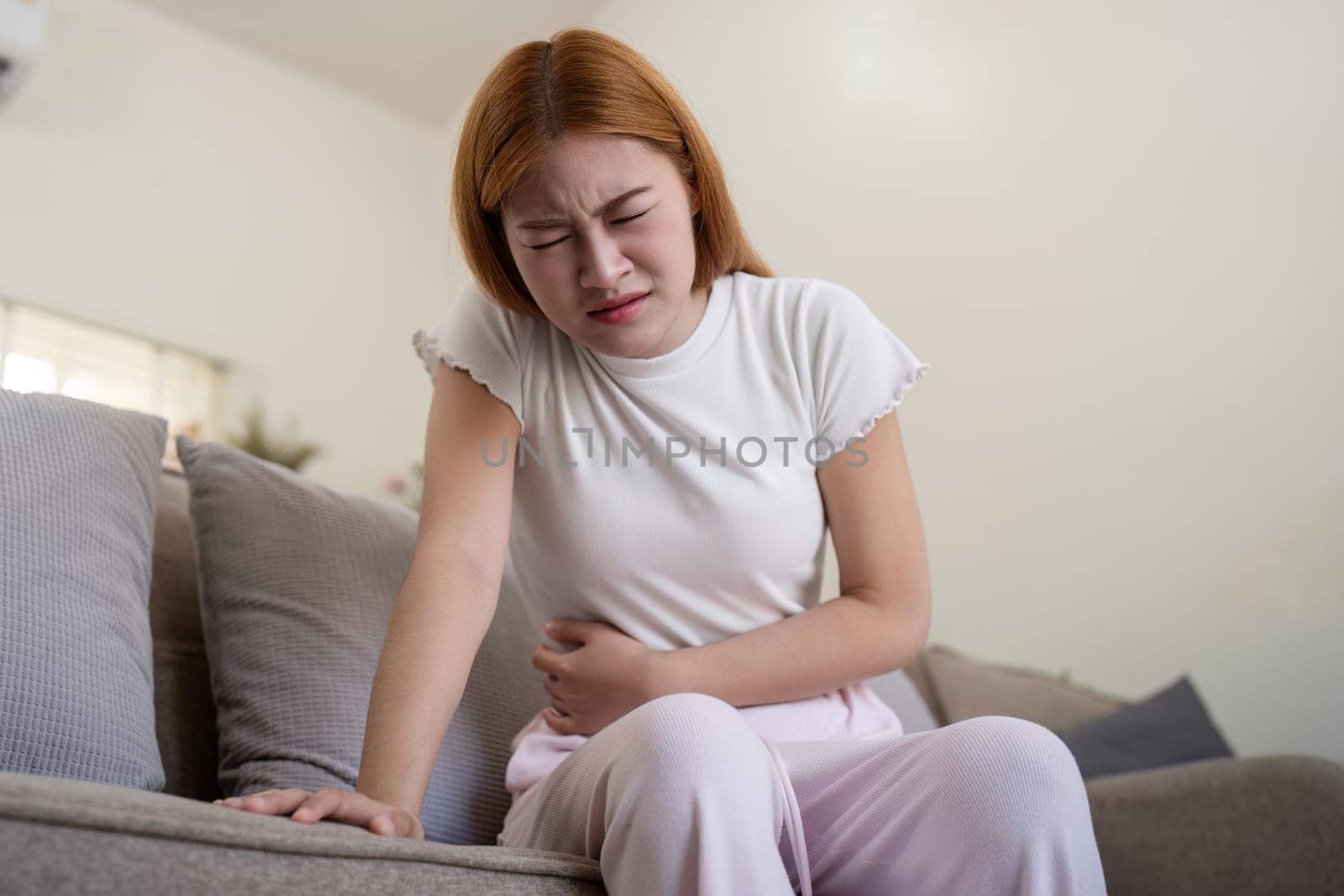 Asian woman having painful from stomach ache at home, Female suffering with abdominal pain.
