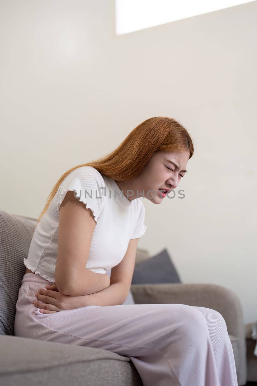 Asian woman having painful from stomach ache at home, Female suffering with abdominal pain by nateemee