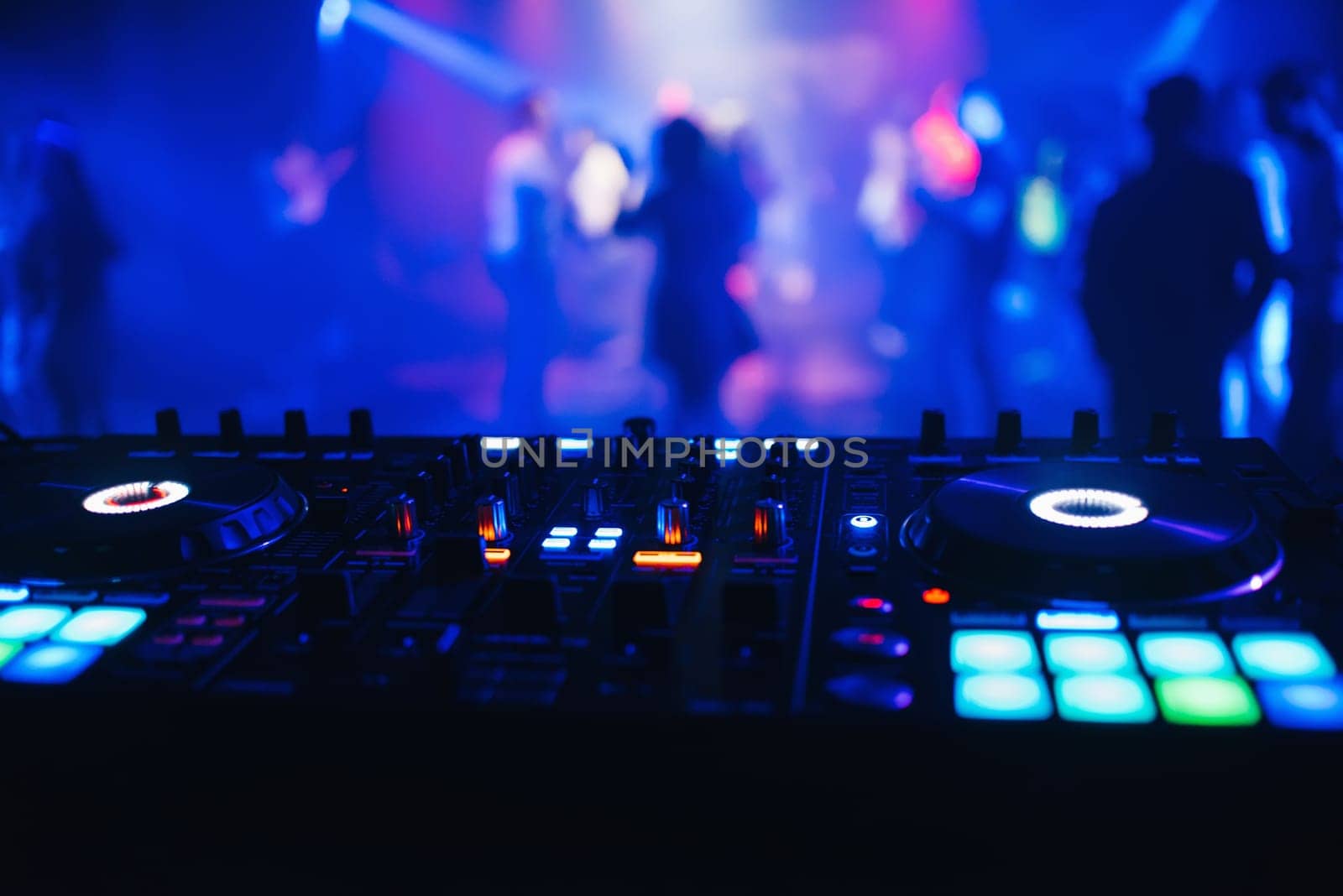 DJ mixer on the table background the night club and dancing people