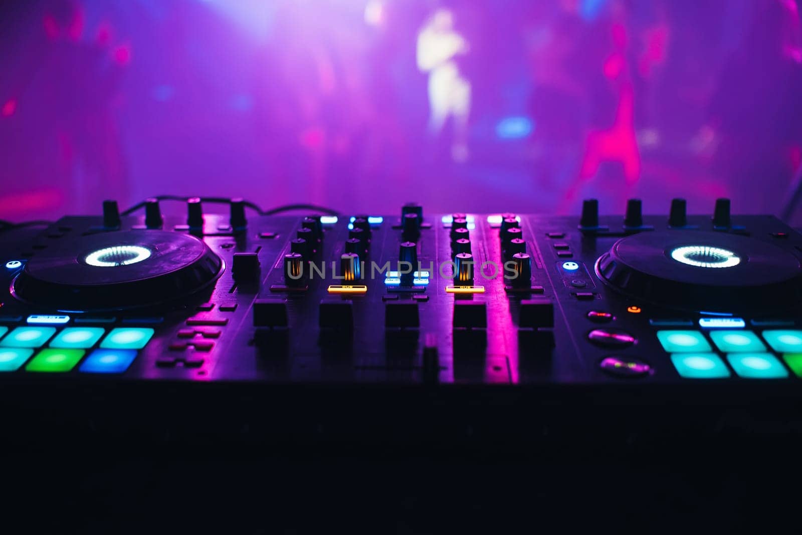 DJ mixer on the table background the night club and dancing people