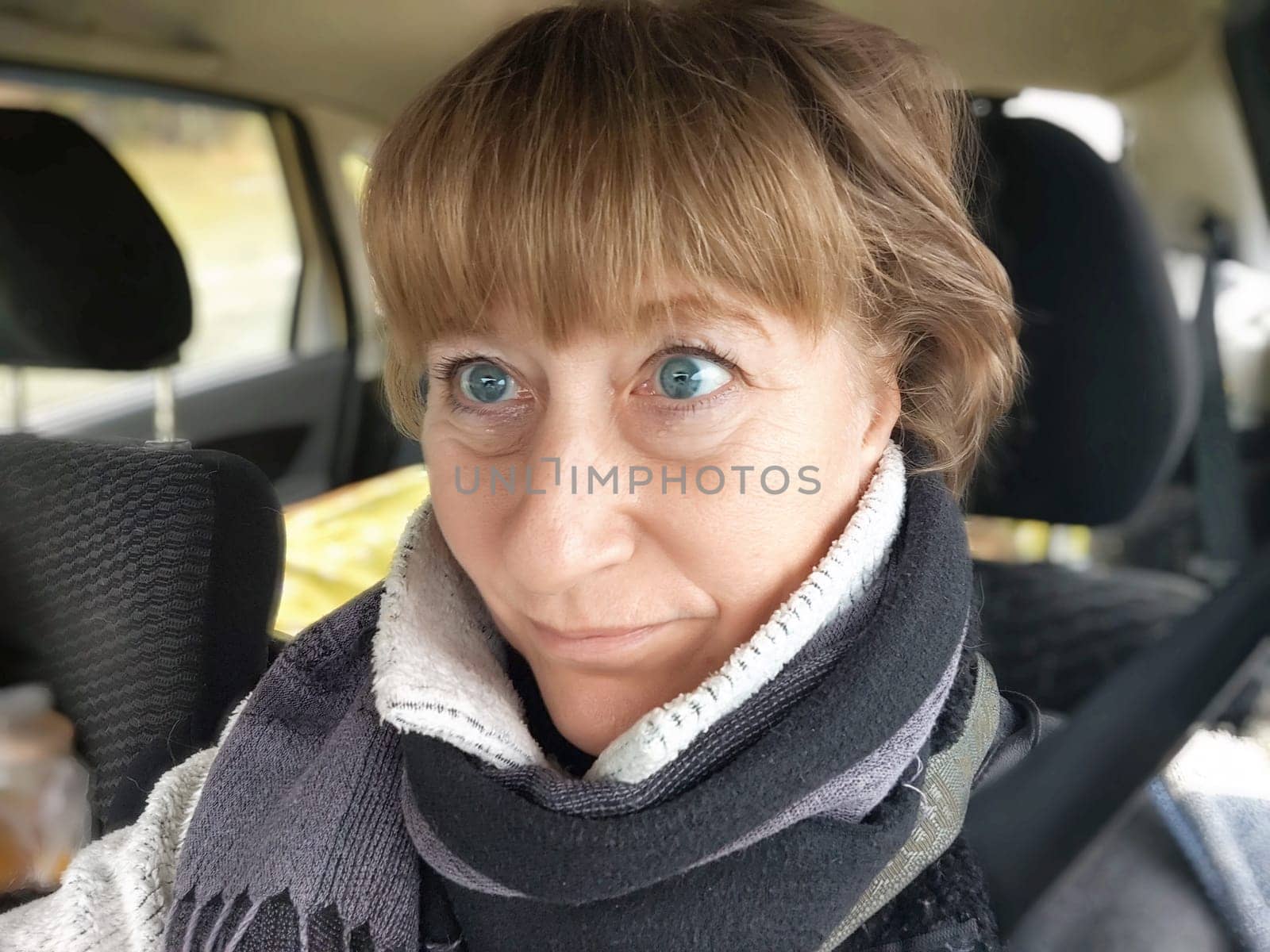 Funny Middle aged woman in a car taking selfie while enjoying drive. Female mature driver posing inside car. Funny happy tourist girl in alone travel by keleny