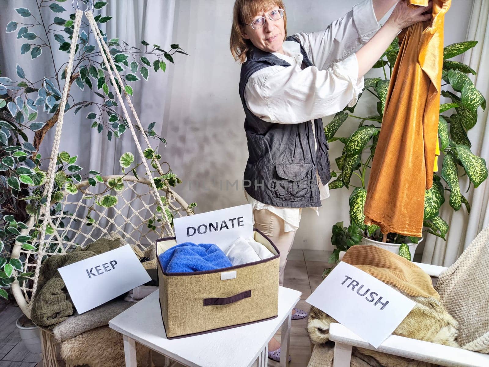 Middle-Aged Woman Sorting Belongings With KonMari Method. Mature woman categorizes items into keep and discard piles