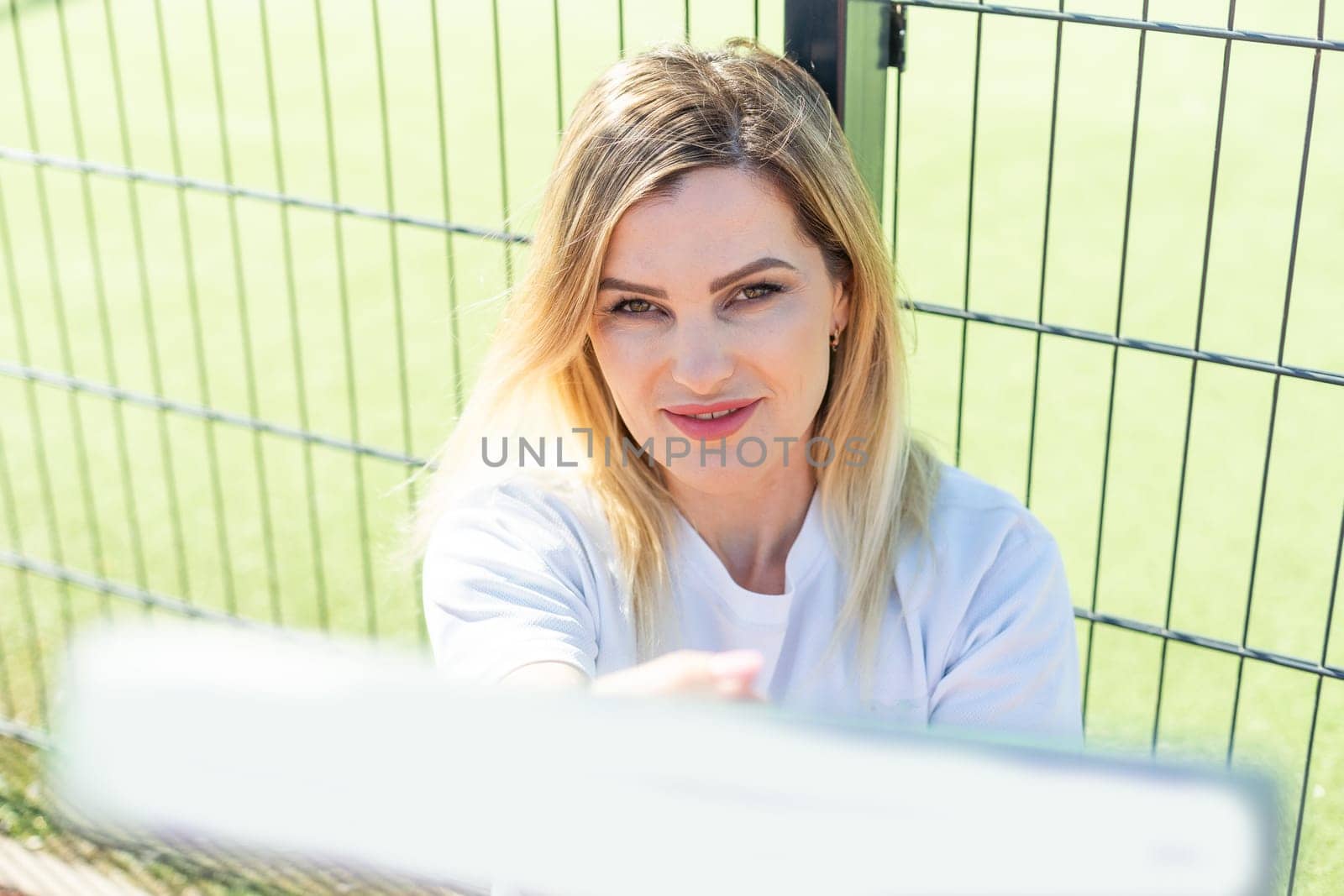 Happy female paddle tennis player during practice on outdoor court looking at camera. Copy space. High quality photo