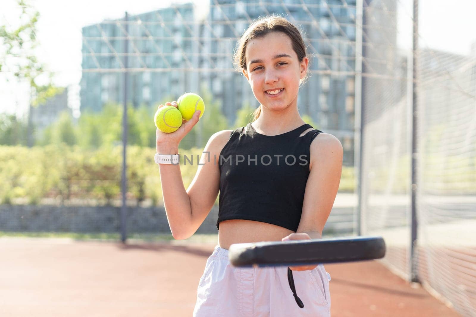 Teenage girl holding padel racquet in hand and ready to return ball while playing in court. High quality photo