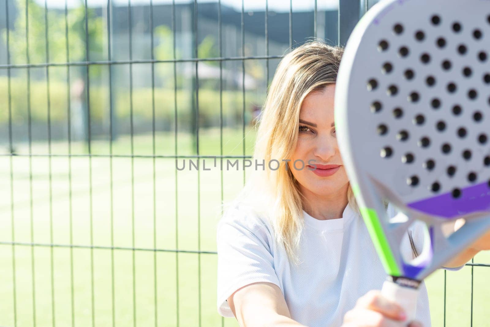 Happy female paddle tennis player during practice on outdoor court looking at camera. Copy space. High quality photo