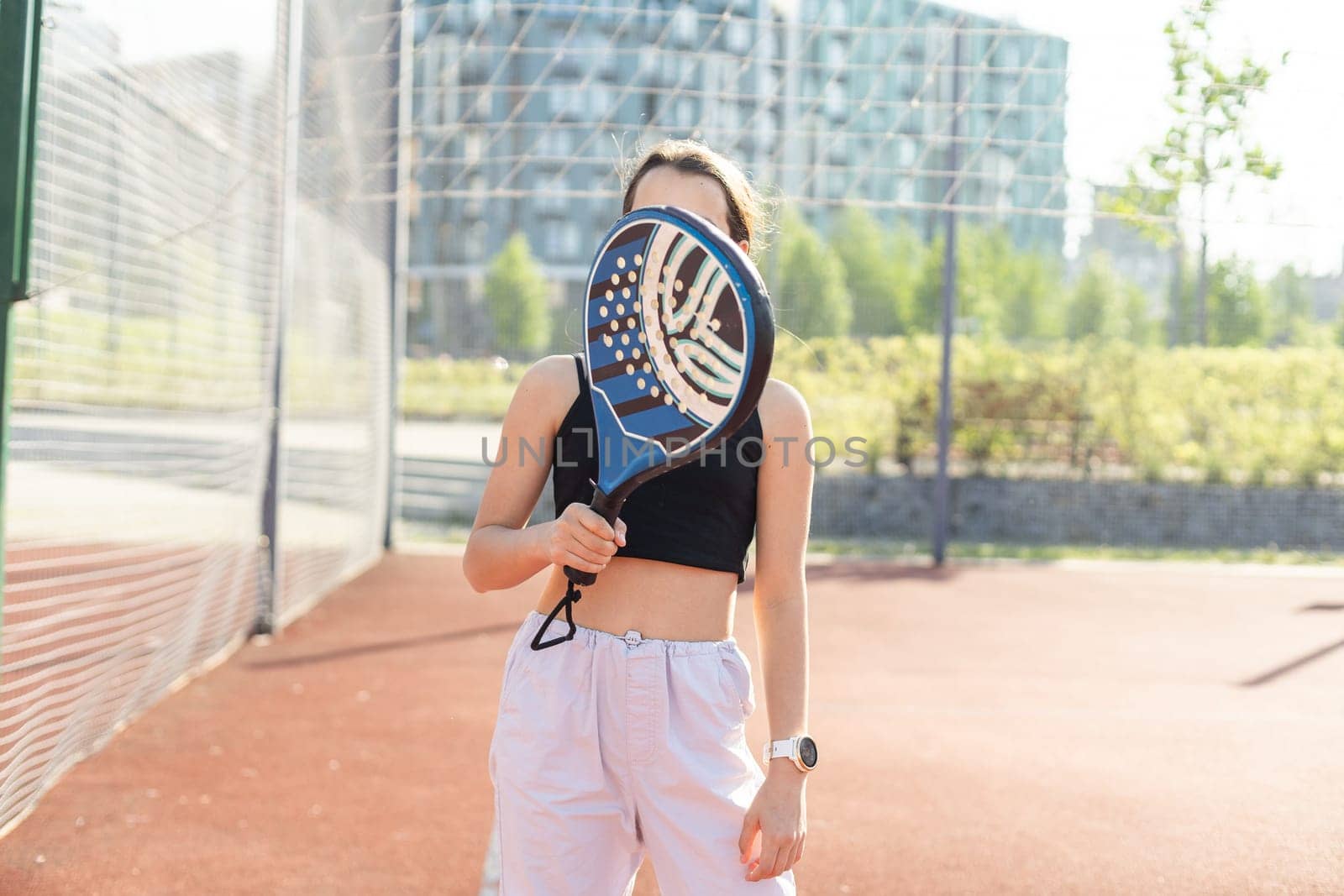Padel tennis player with racket and ball in hands. Girl athlete with paddle racket on court outdoors. Sport concept. Download a high quality photo for the design of a sports app or web site. High quality photo