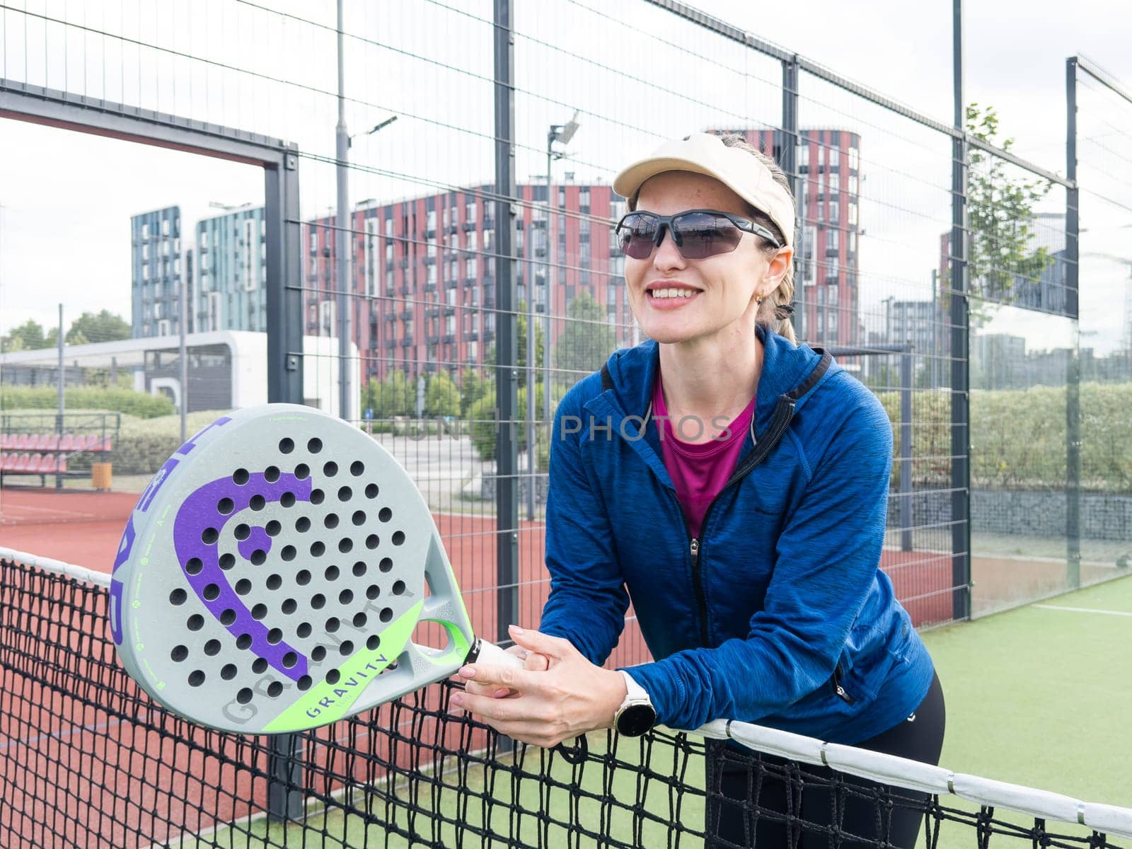Ukraine Kyiv, May 10 2024. Portrait of smiling woman with padel tennis racket head at court by Andelov13