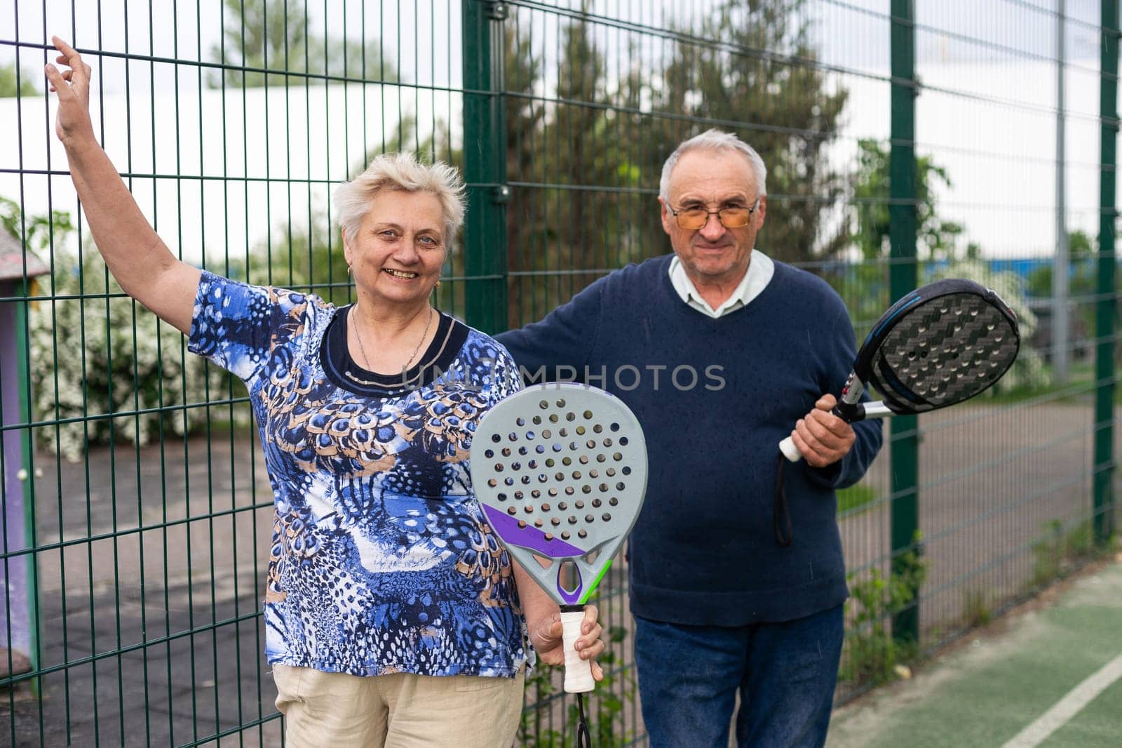 Portrait of sporty fit senior woman playing padel on open court on summer day, ready to hit ball. Health and active lifestyle concept.. High quality photo