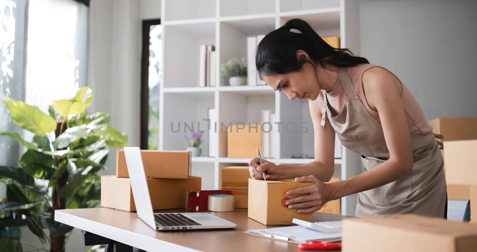 Young asian woman packing boxes in warehouse..