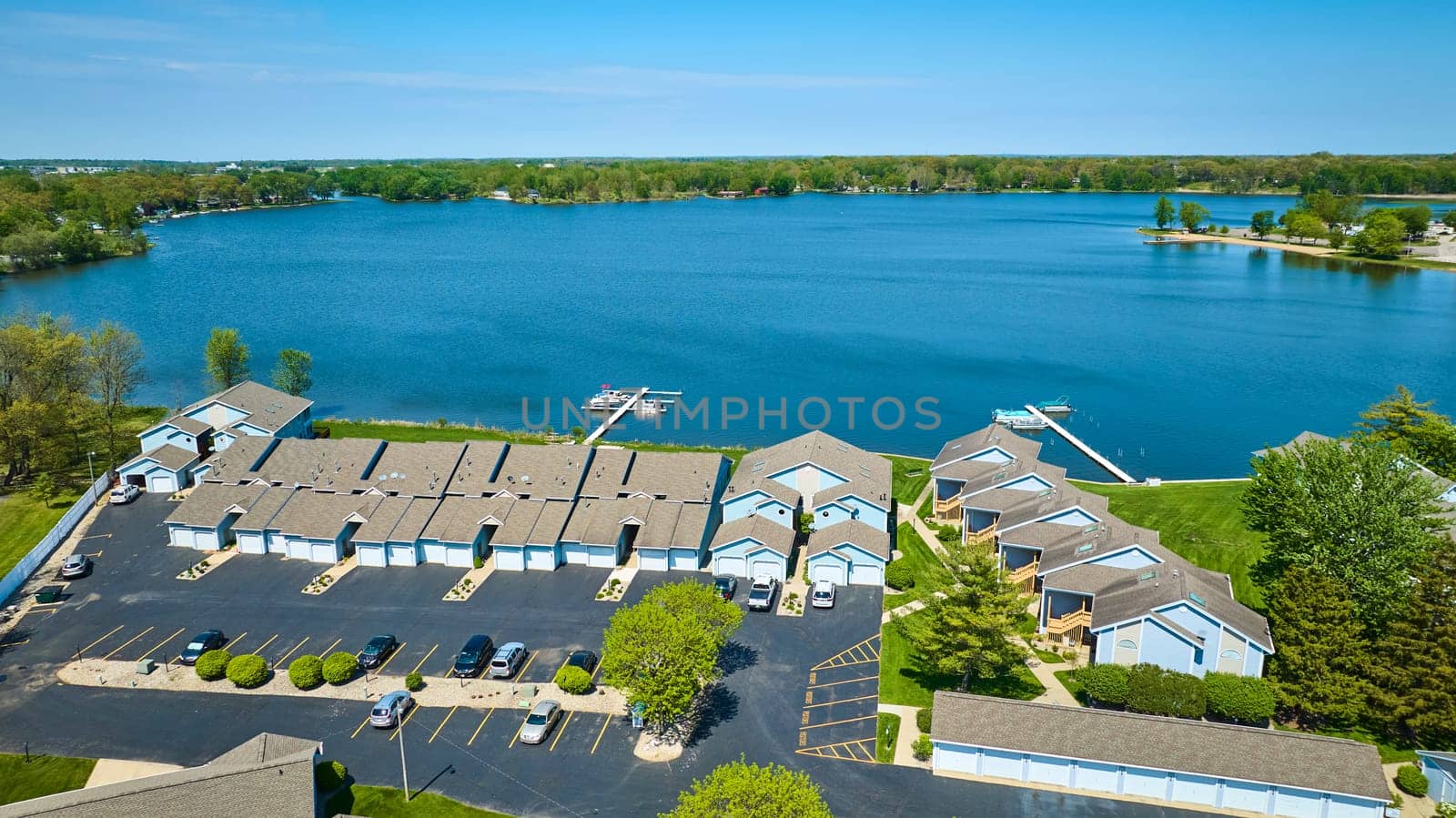 Aerial view of a peaceful lakeside community in Warsaw, Indiana, showcasing neat townhouses and recreational boating.