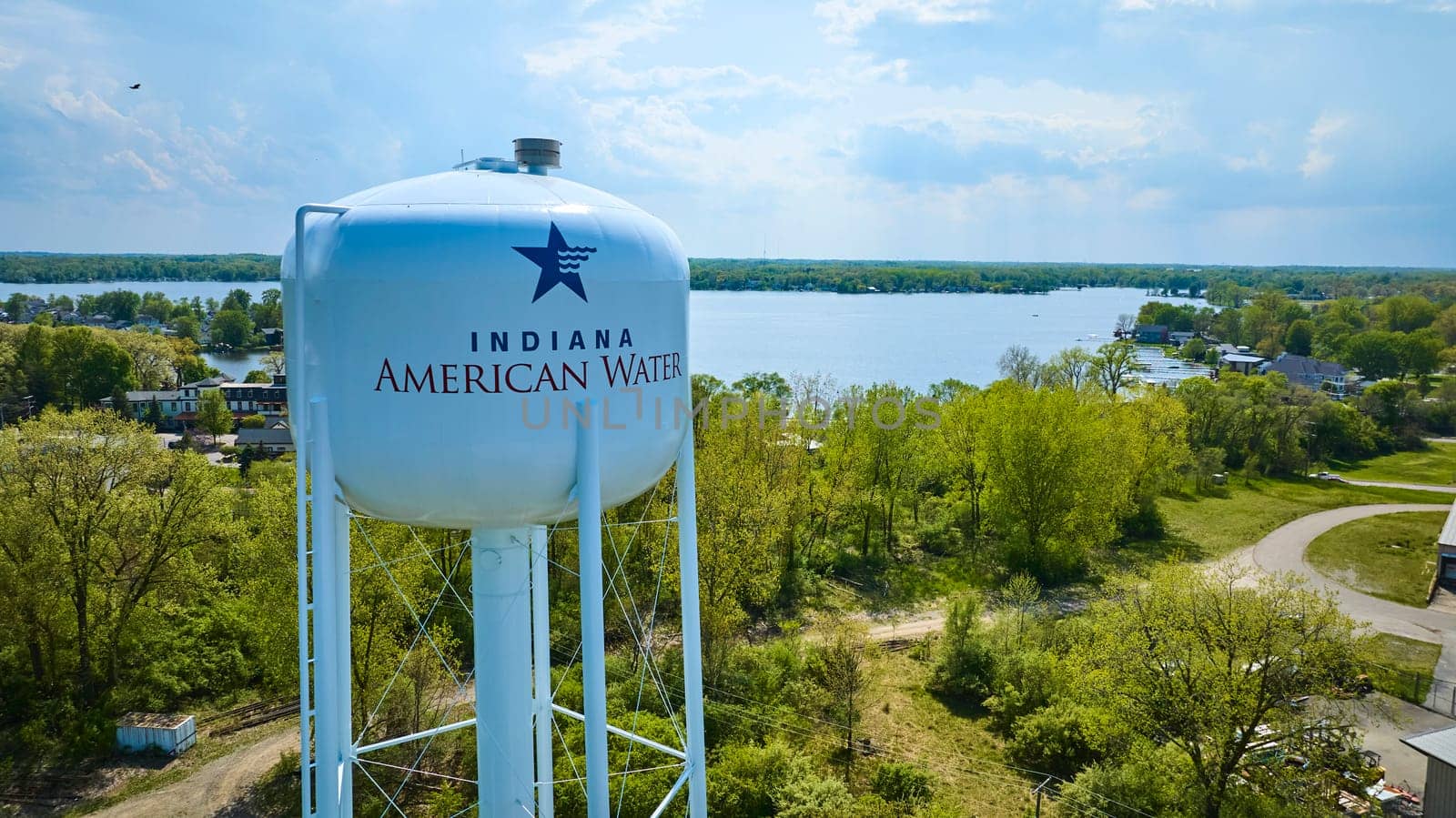 Elevated view of Indiana American Water tower in lush Warsaw setting, showcasing community infrastructure and natural beauty.