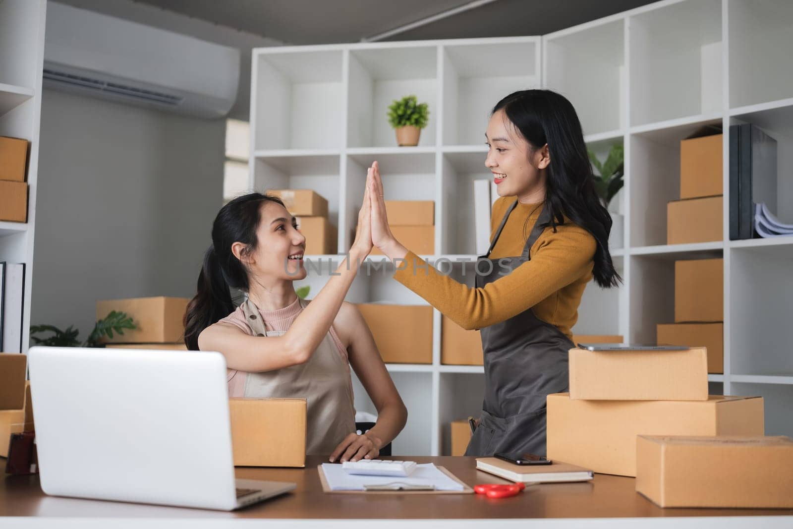 Asian businesswomen giving high-five in office. Concept of teamwork and business celebration by wichayada