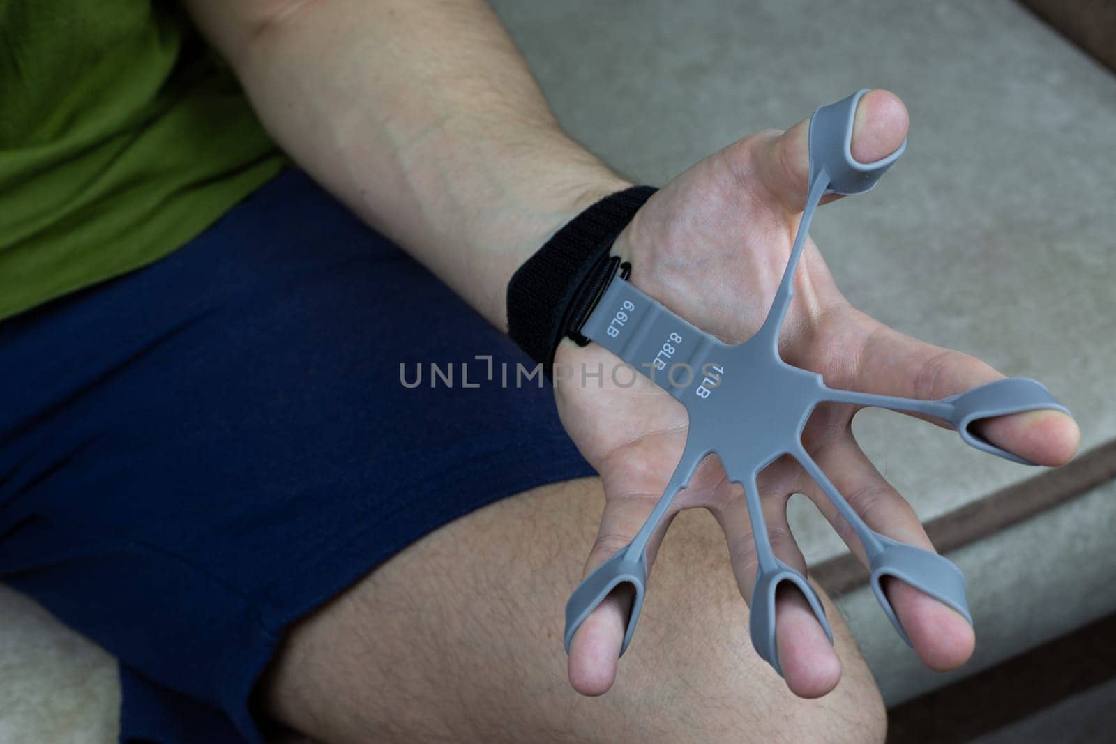 Finger trainer in stretched position while performing an exercise to develop hand and finger strength