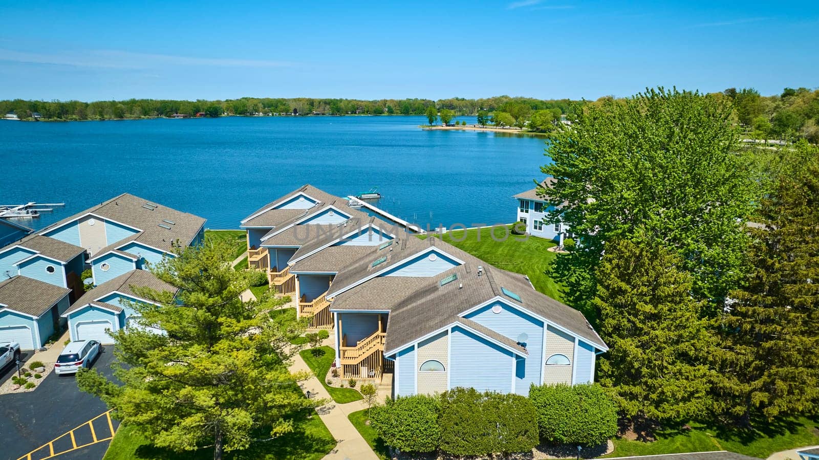 Aerial view of a peaceful lakeside community in Warsaw, Indiana, showcasing homes with private docks and vibrant greenery.