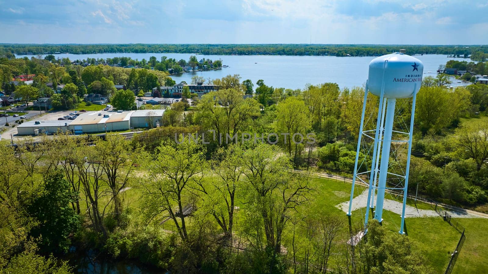 Aerial view of Indiana American Water tower, surrounded by lush greenery and a lively lake community.