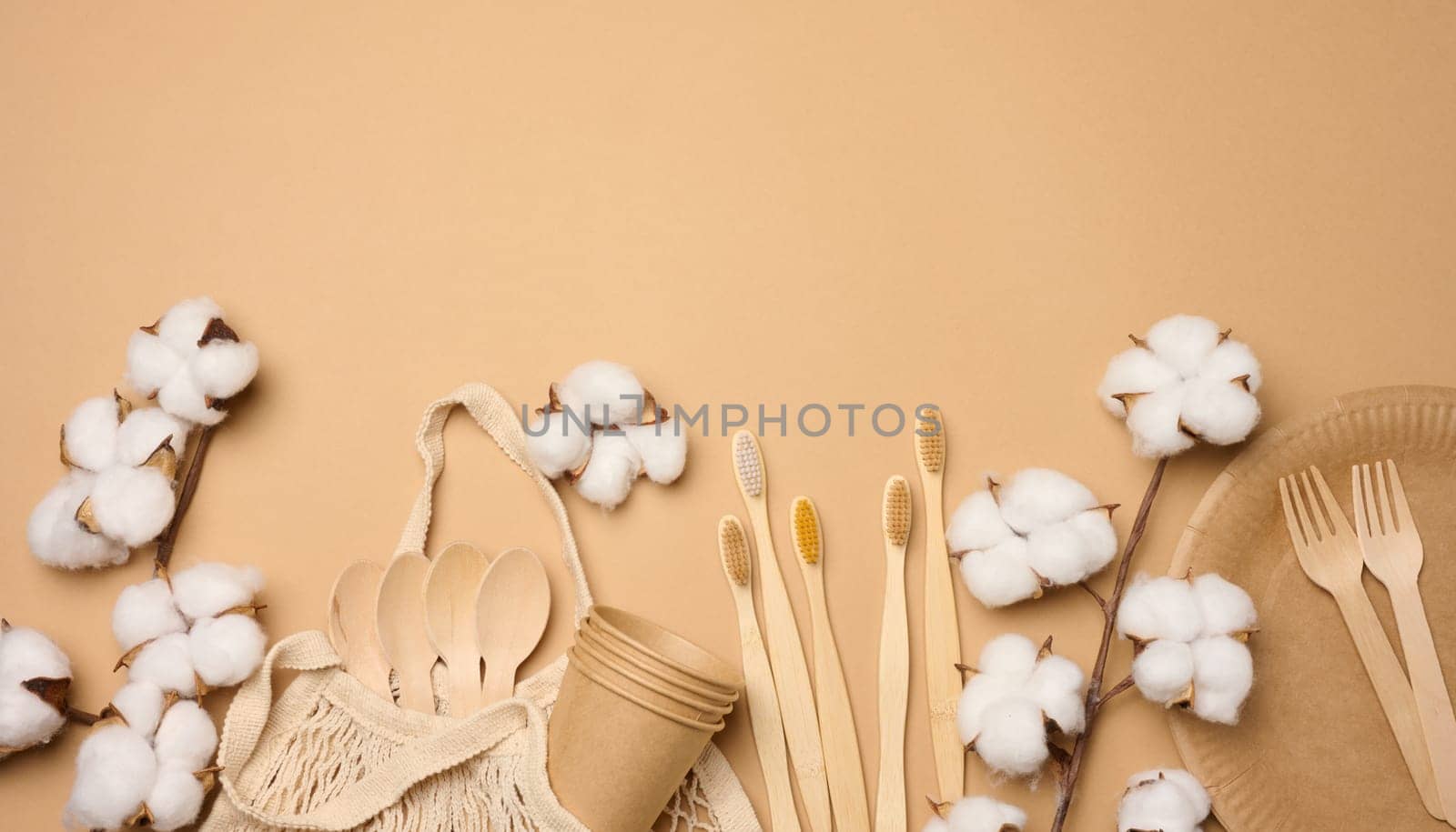 Cotton bag, wooden spoon, plates and cups on a brown background. Waste recycling concept, zero waste