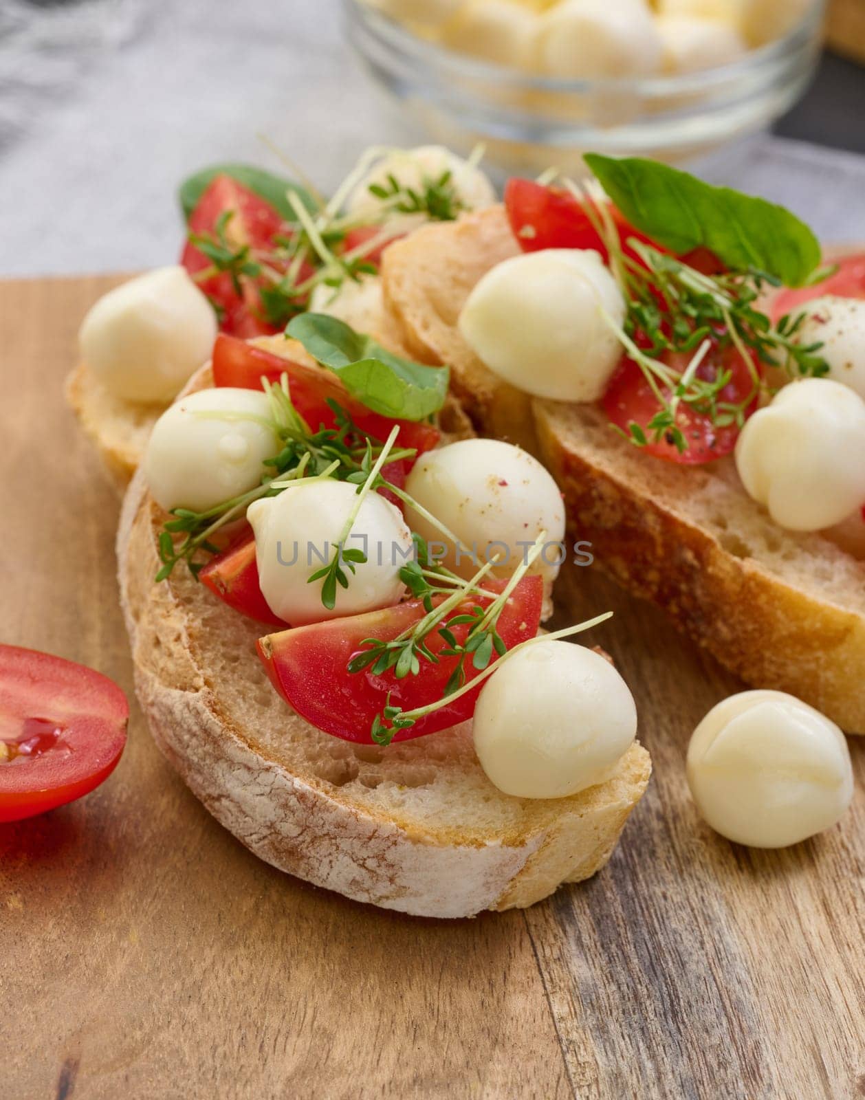 Round mozzarella, cherry tomatoes and microgreens on a piece of white bread, a healthy sandwich