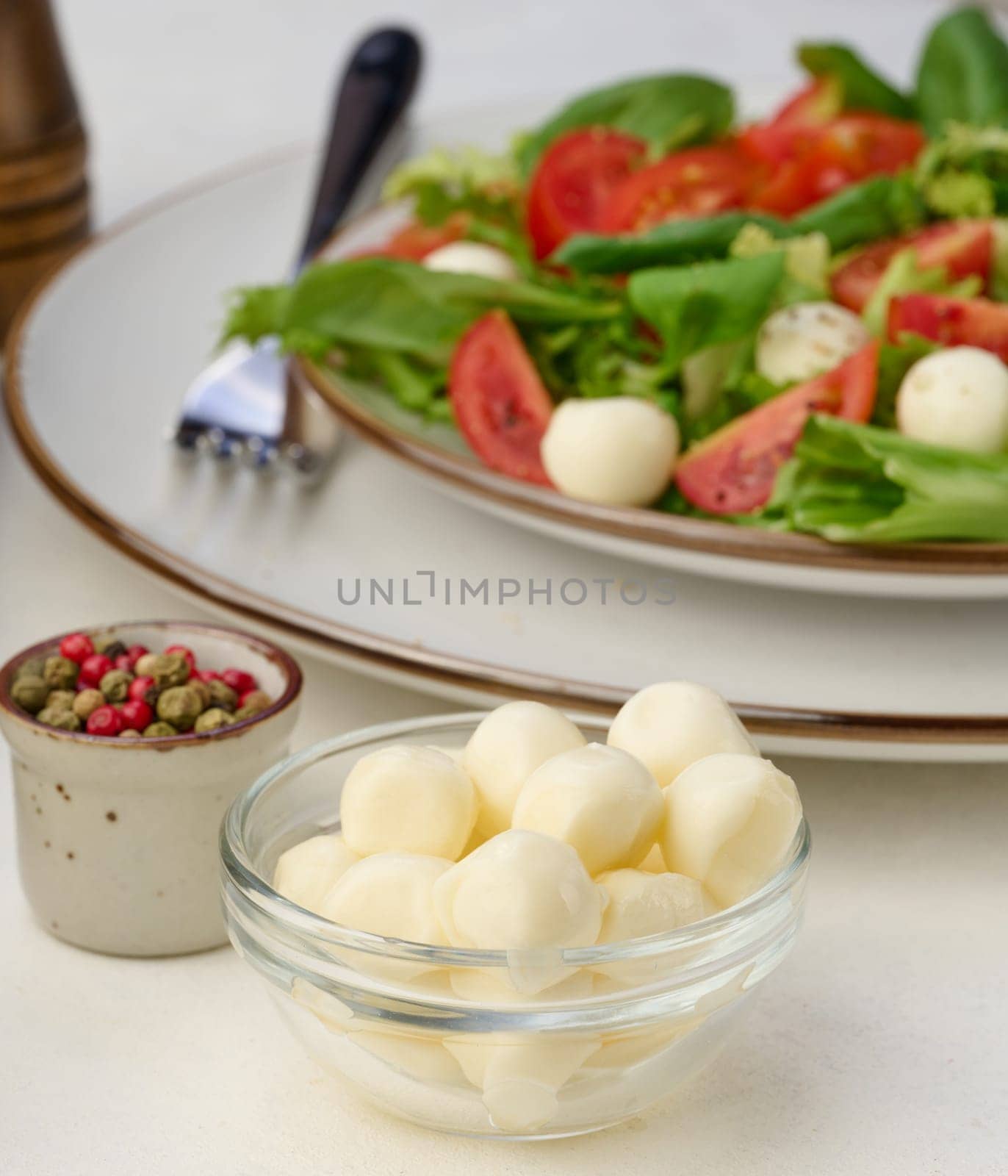Mozzarella balls in glass bowl and salad on a white background by ndanko