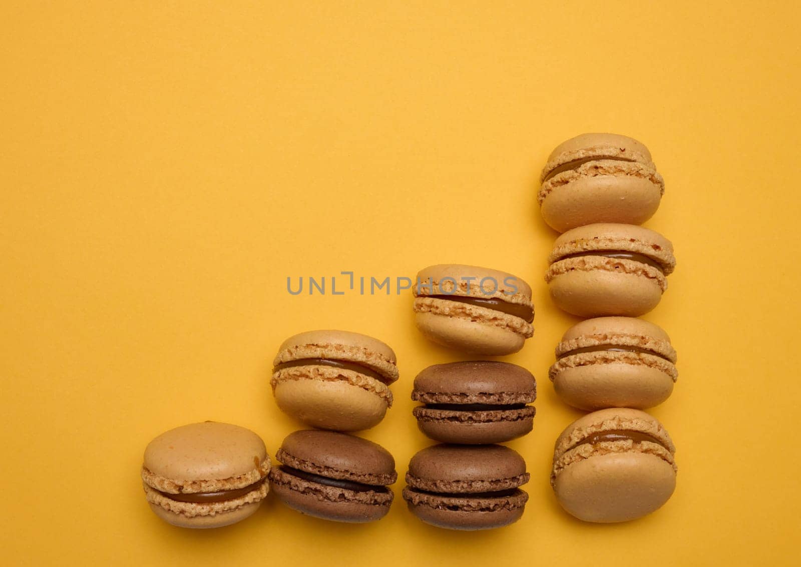 Chocolate macarons on a yellow background, dessert. Top view