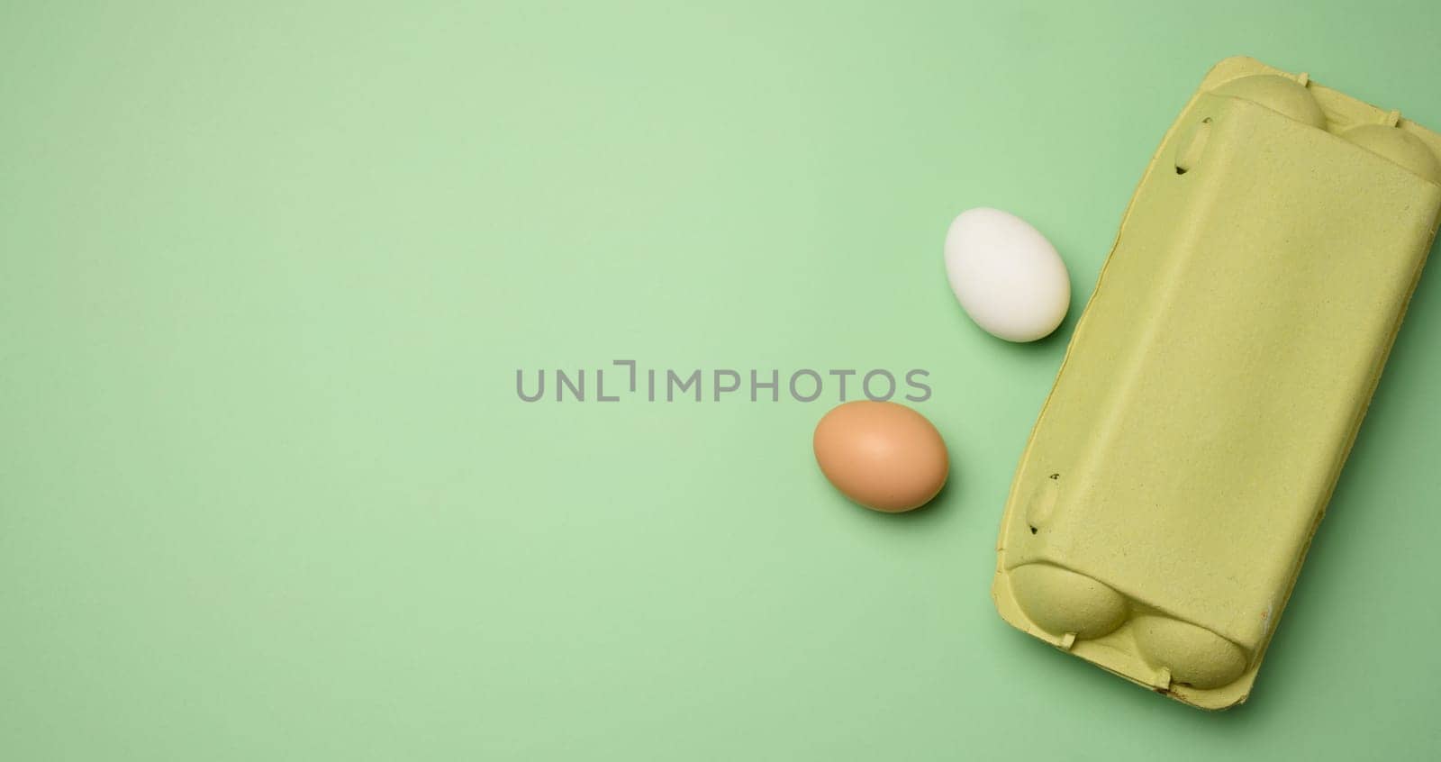 Chicken egg and paper storage box on green background, top view by ndanko