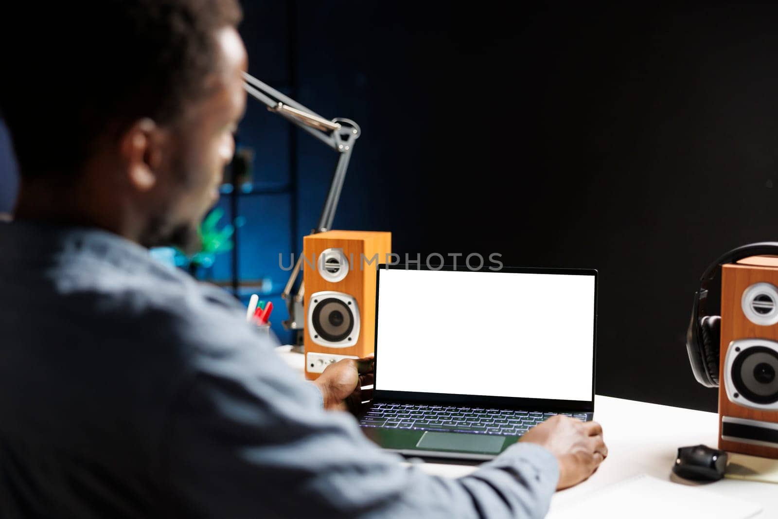 African american freelancer examines white screen on laptop, working from home and using blank chromakey display on wireless computer. Independent contractor looks at copyspace layout.