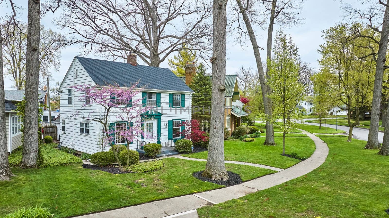 Idyllic Fort Wayne suburb in spring, white house with pink blooms, perfect for real estate showcases.