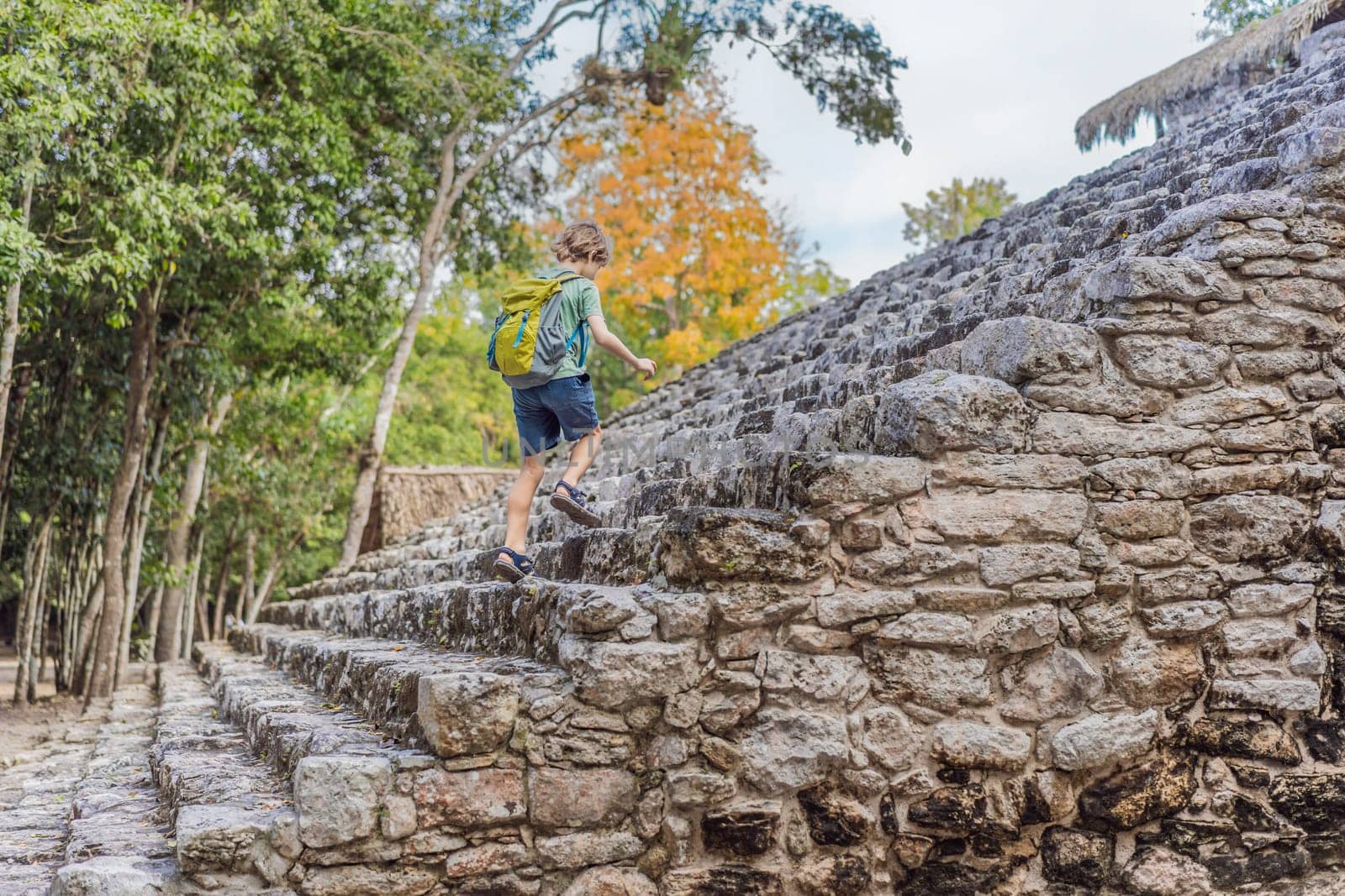 Boy tourist at Coba, Mexico. Ancient mayan city in Mexico. Coba is an archaeological area and a famous landmark of Yucatan Peninsula. Cloudy sky over a pyramid in Mexico.