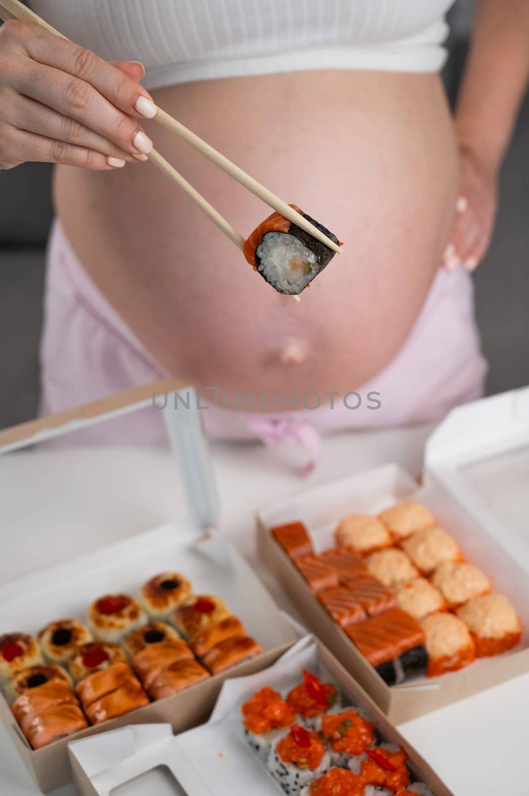 A pregnant woman stands at a table with rolls. Close-up of the belly. by mrwed54