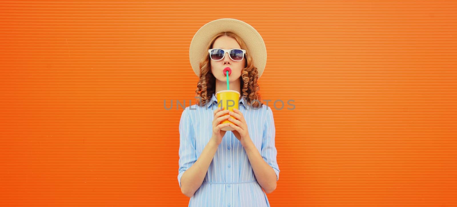 Summer portrait of beautiful young woman with cup of fresh juice wearing hat on blue background by Rohappy