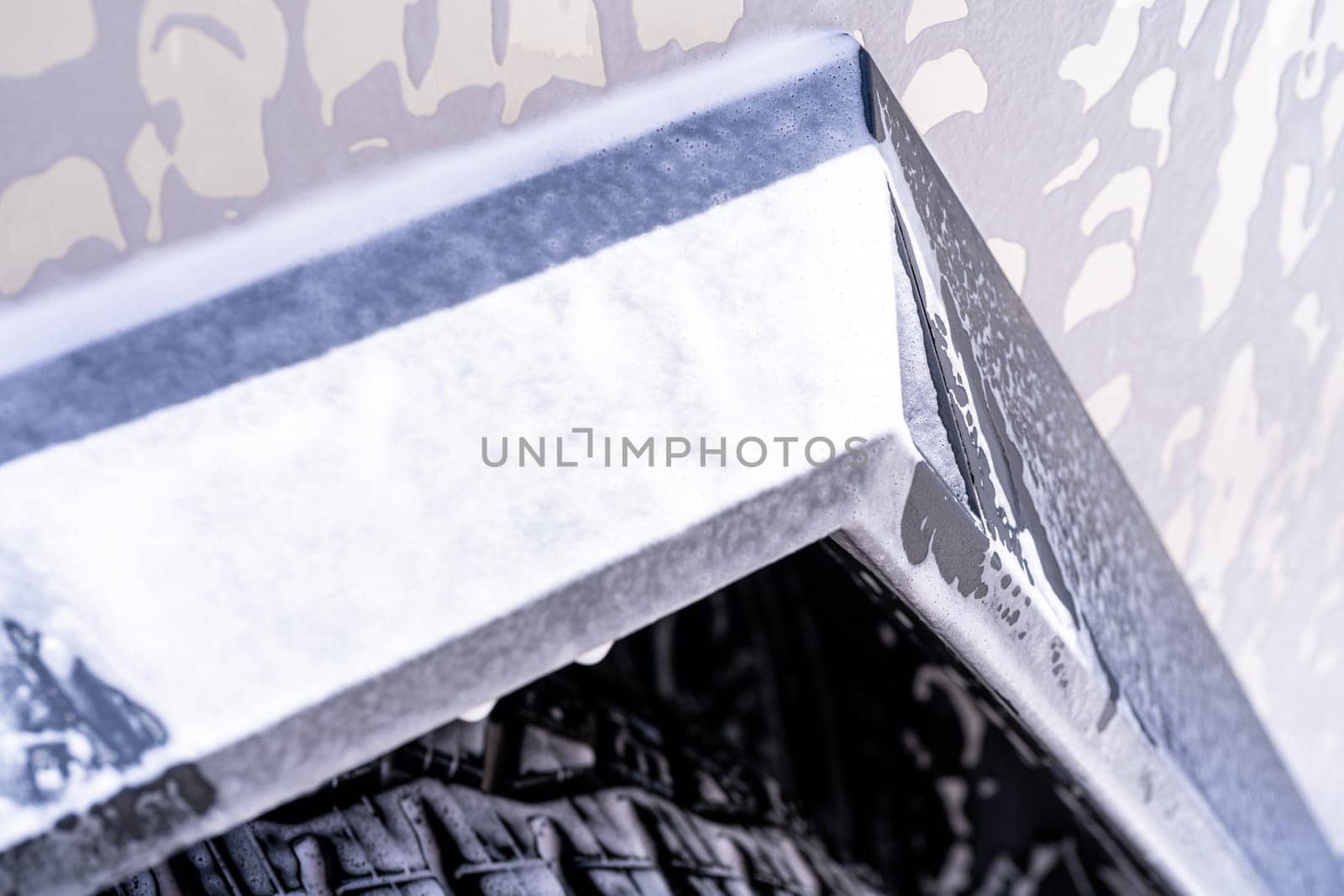 Denver, Colorado, USA-May 5, 2024-This image features a close-up view of the Tesla Cybertruck wheel and angular body design covered in soap and water during a thorough car wash, highlighting the unique textures and robust details of the electric truck.